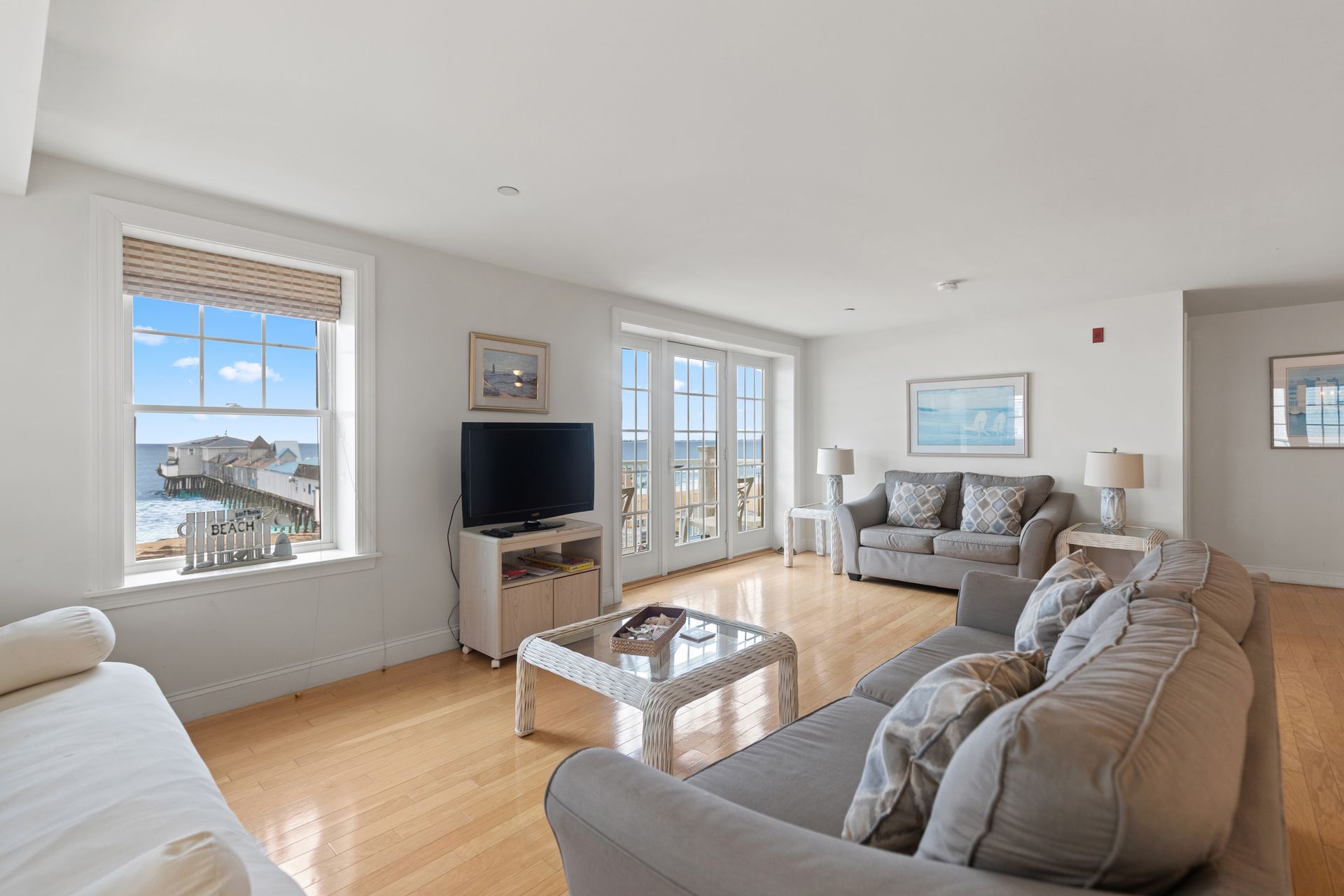 A living room with a couch , chair , television and a view of the ocean.
