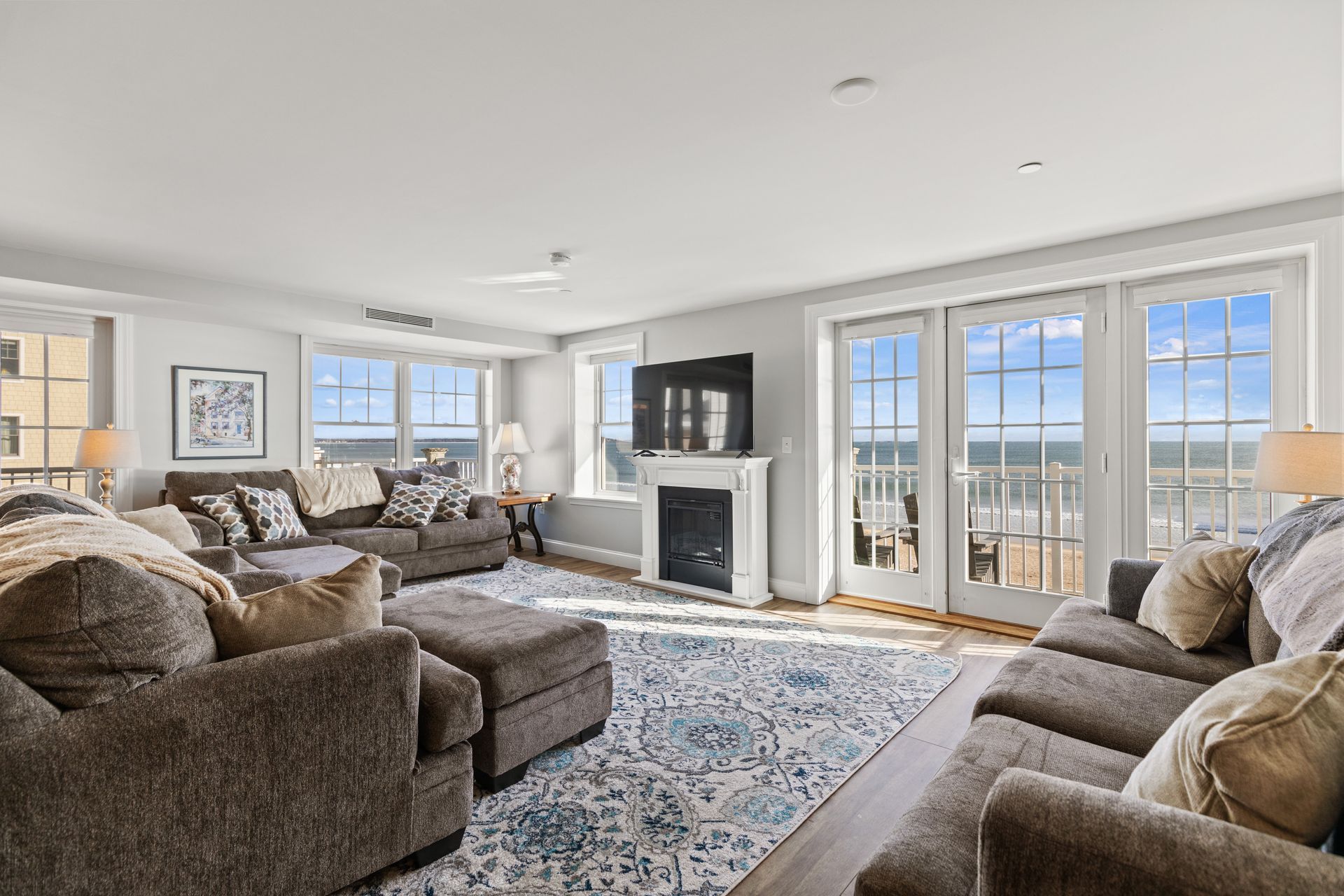 A living room filled with furniture and a fireplace with a view of the ocean.