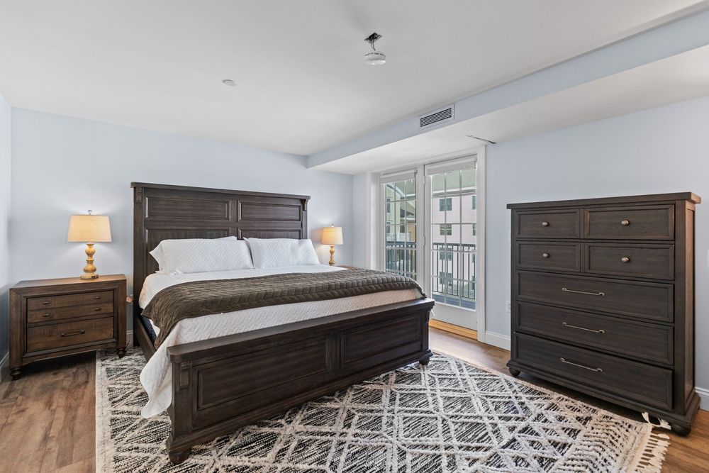 A bedroom with a large bed , dresser , chair and mirror.