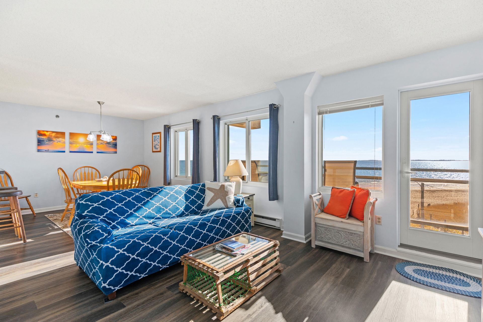 A living room with a blue couch and a view of the ocean.