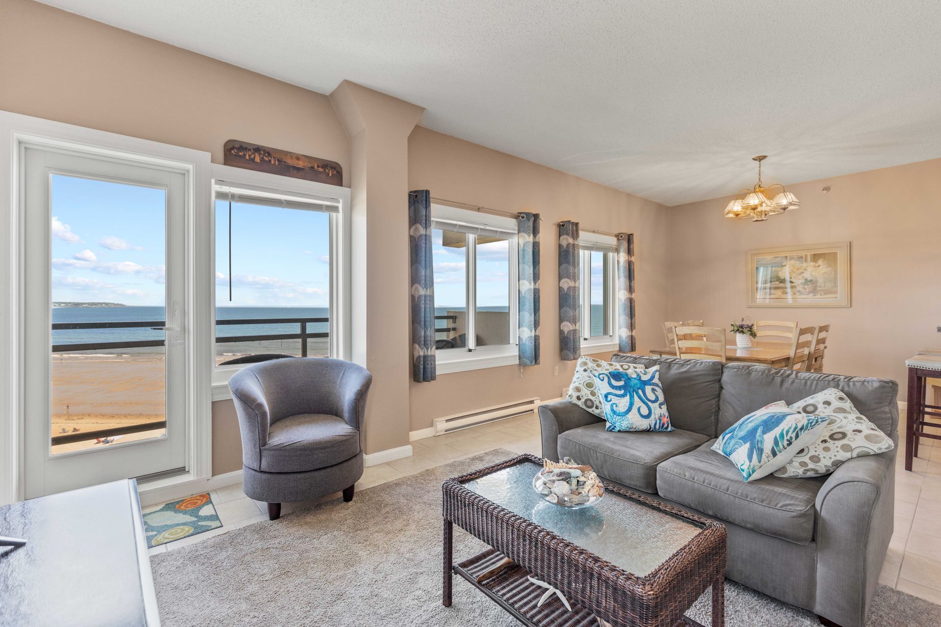 A living room with a couch , chair , coffee table and a view of the ocean.
