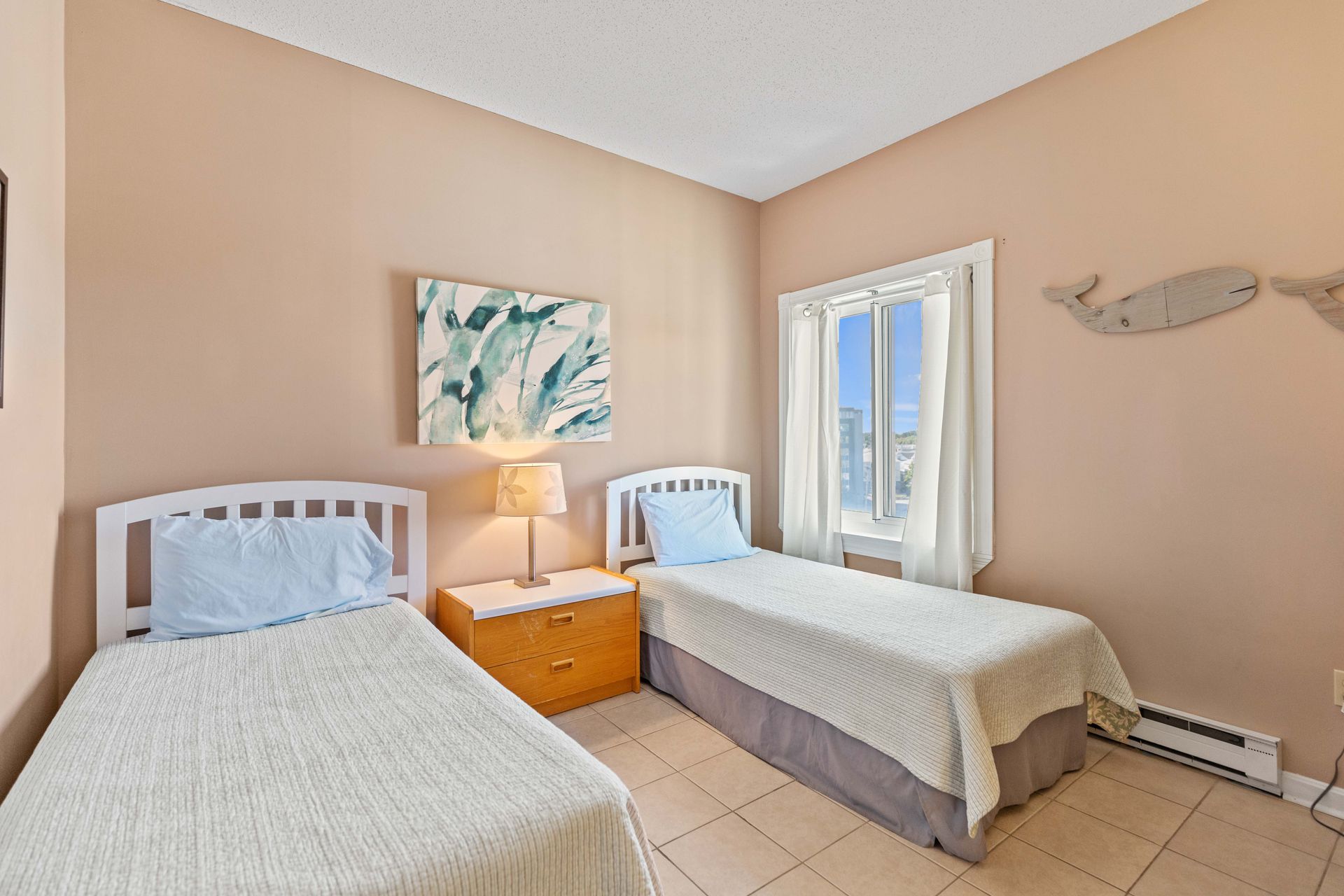A bedroom with two twin beds and a window.