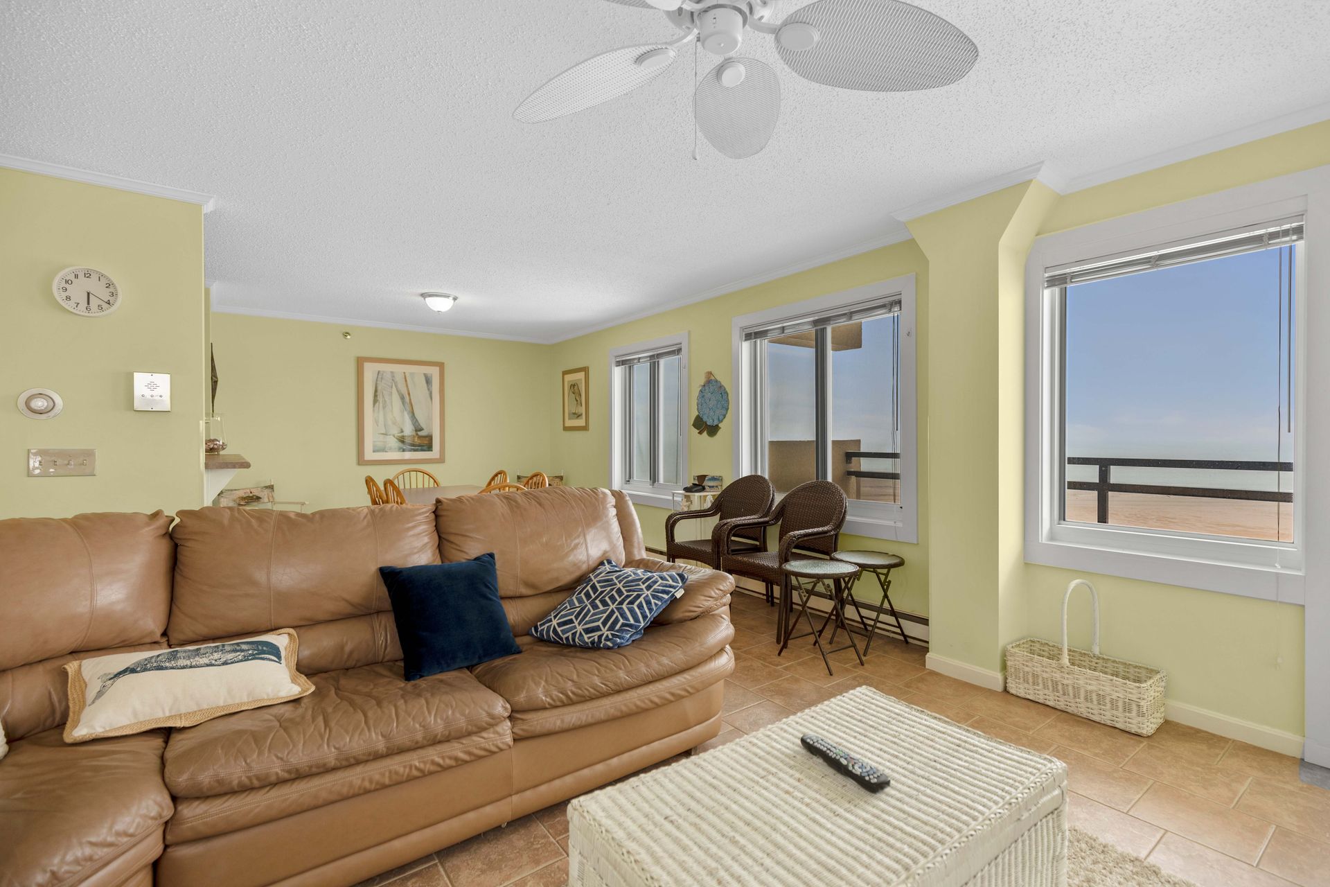 A living room with a couch , table , chairs and a ceiling fan.