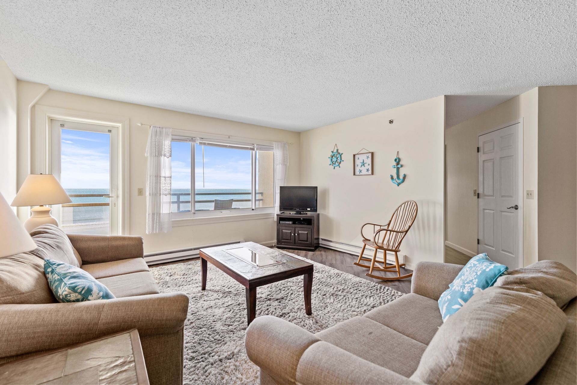 A living room with a couch , chair , coffee table and television.