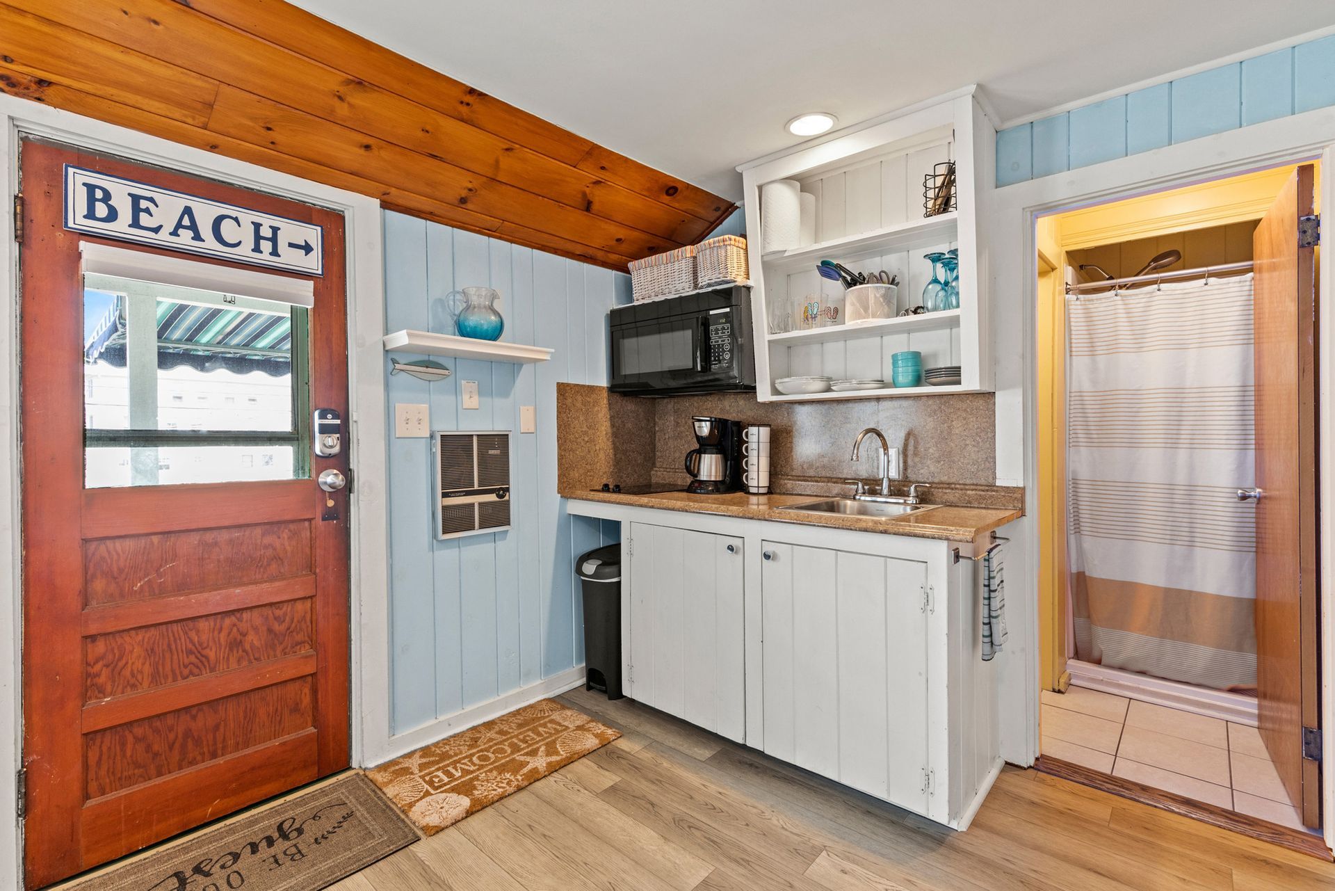 Small kitchen: light blue walls, white cabinets, wooden door with 