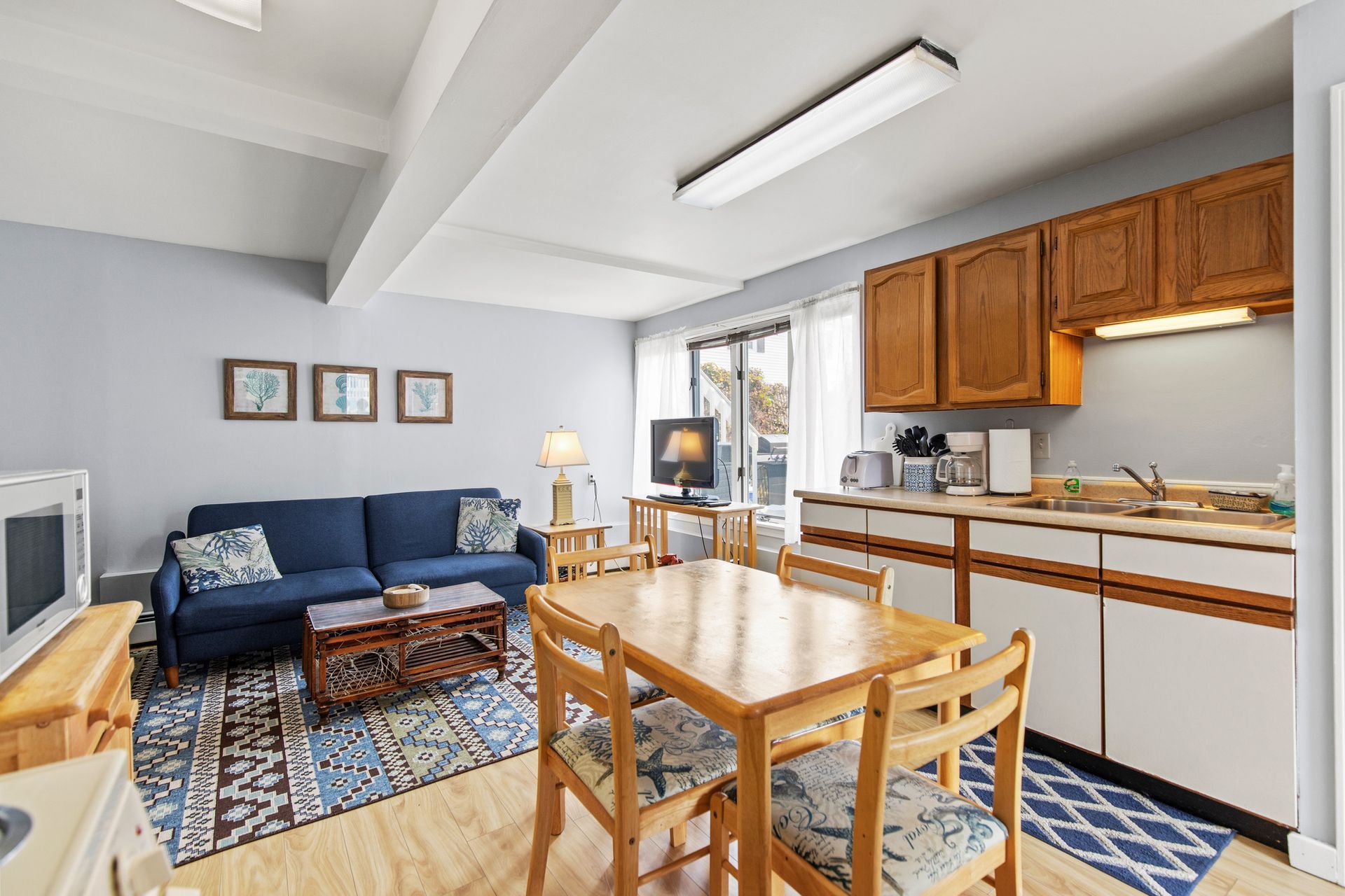 A living room with a blue couch and a table and chairs