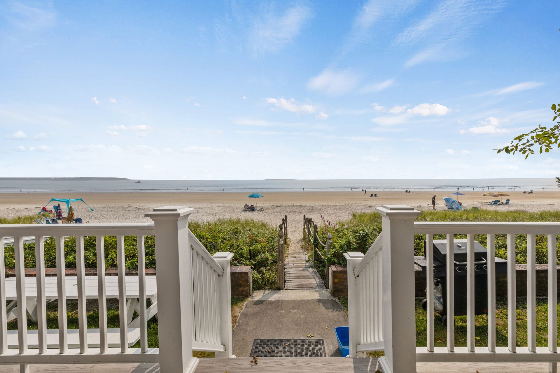 A view of the beach from a deck with stairs leading to it.
