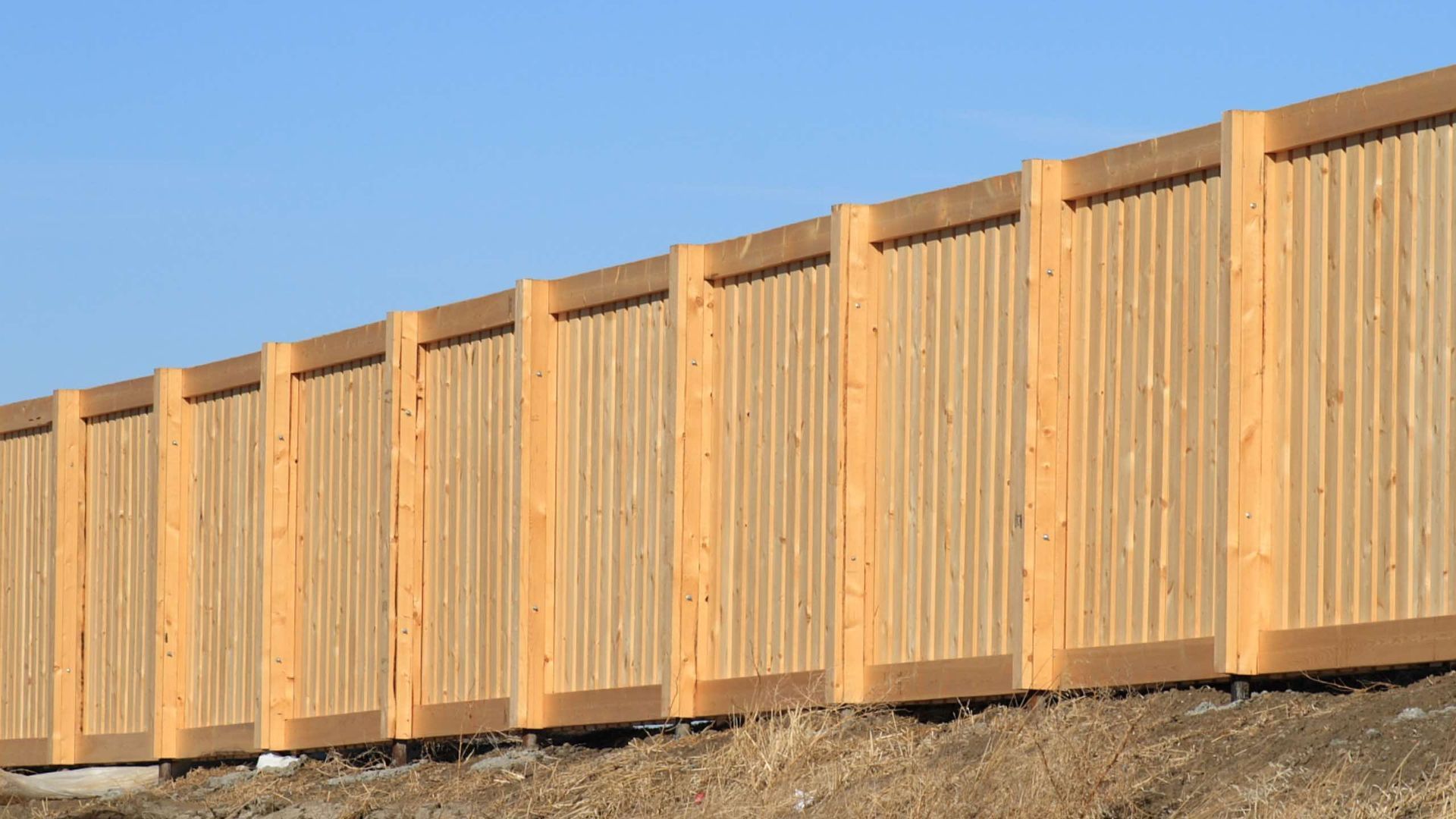 A wooden fence with a blue sky in the background