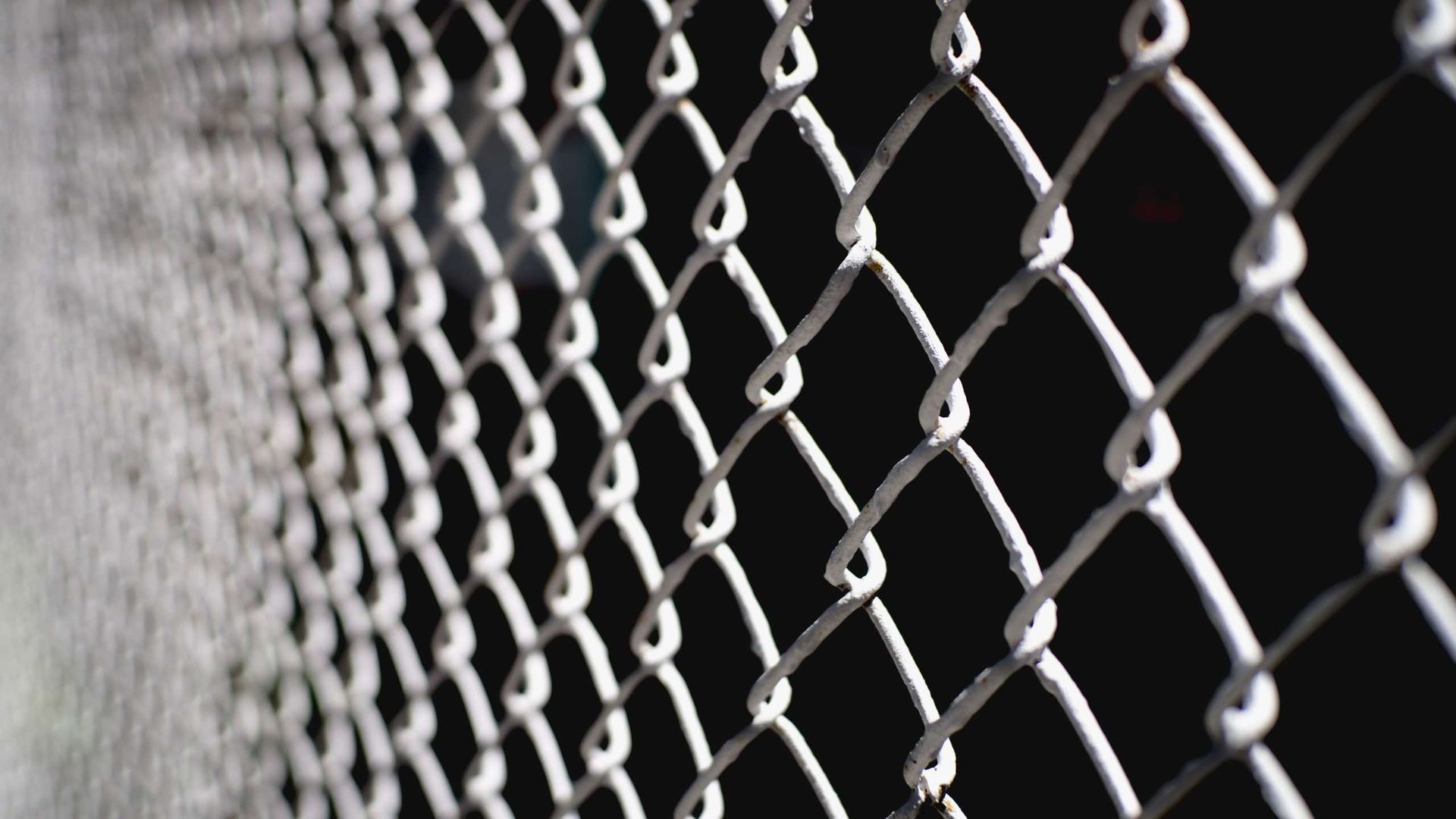 A close up of a chain link fence on a black background.
