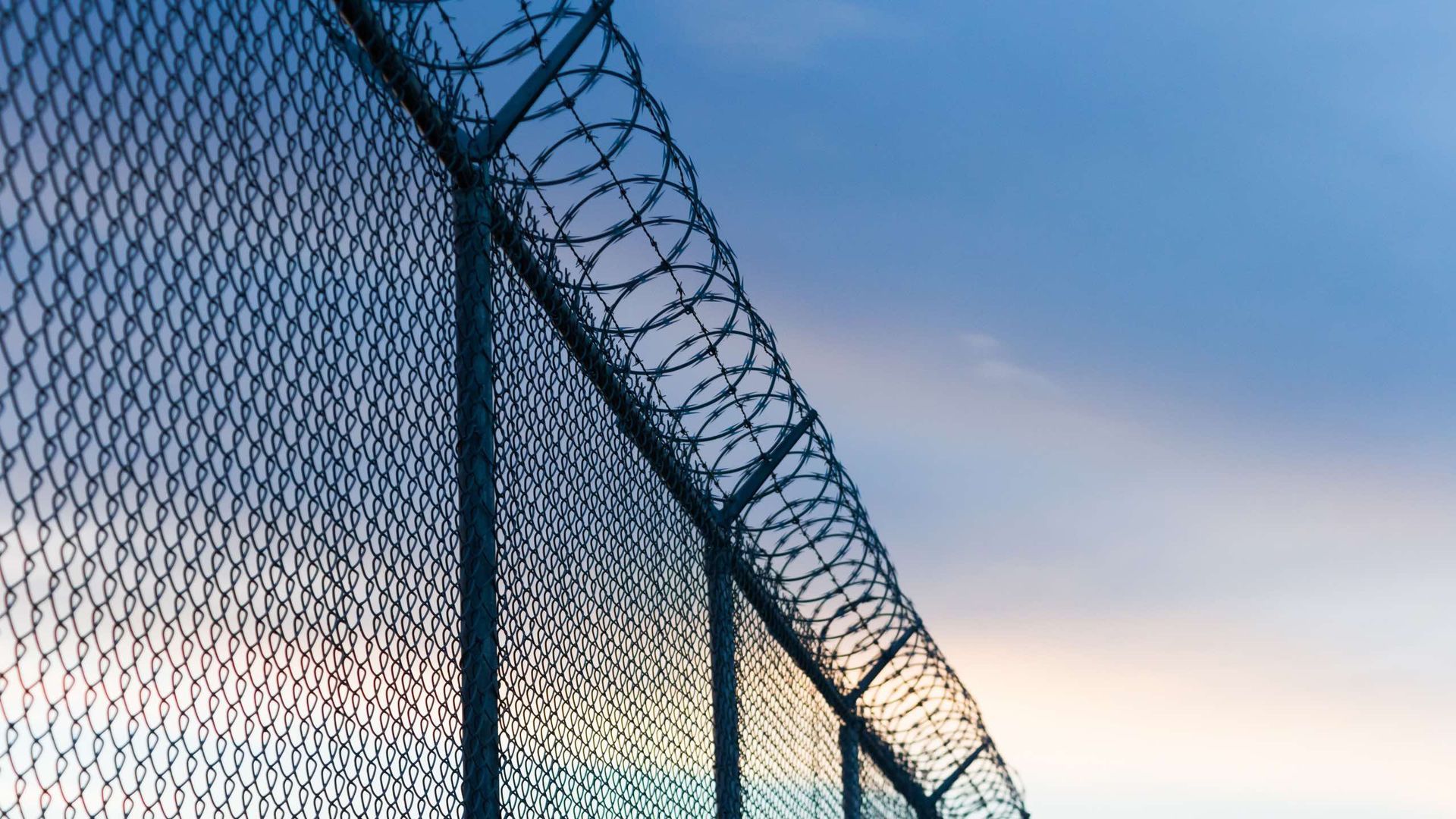 A barbed wire fence with a blue sky in the background.