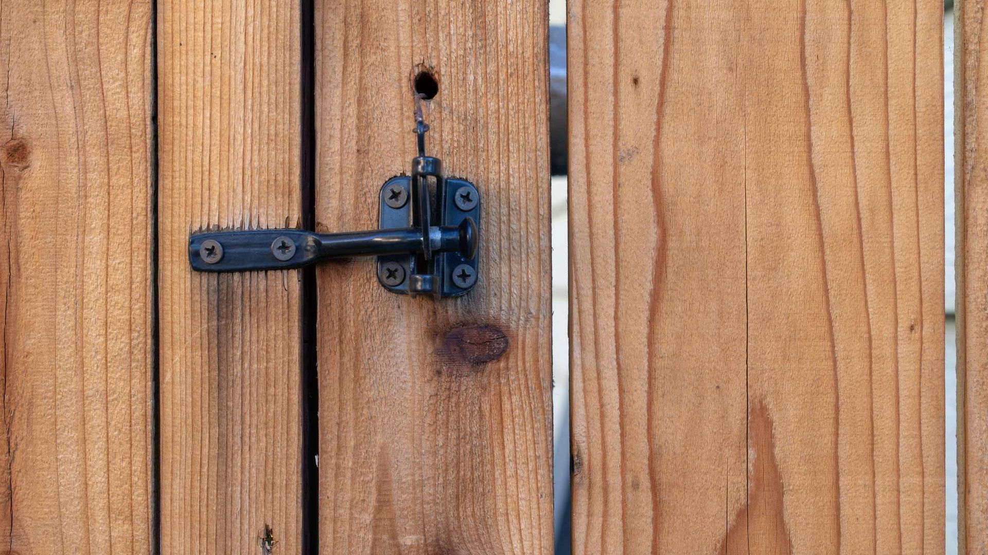 A close up of a wooden fence with a latch on it.