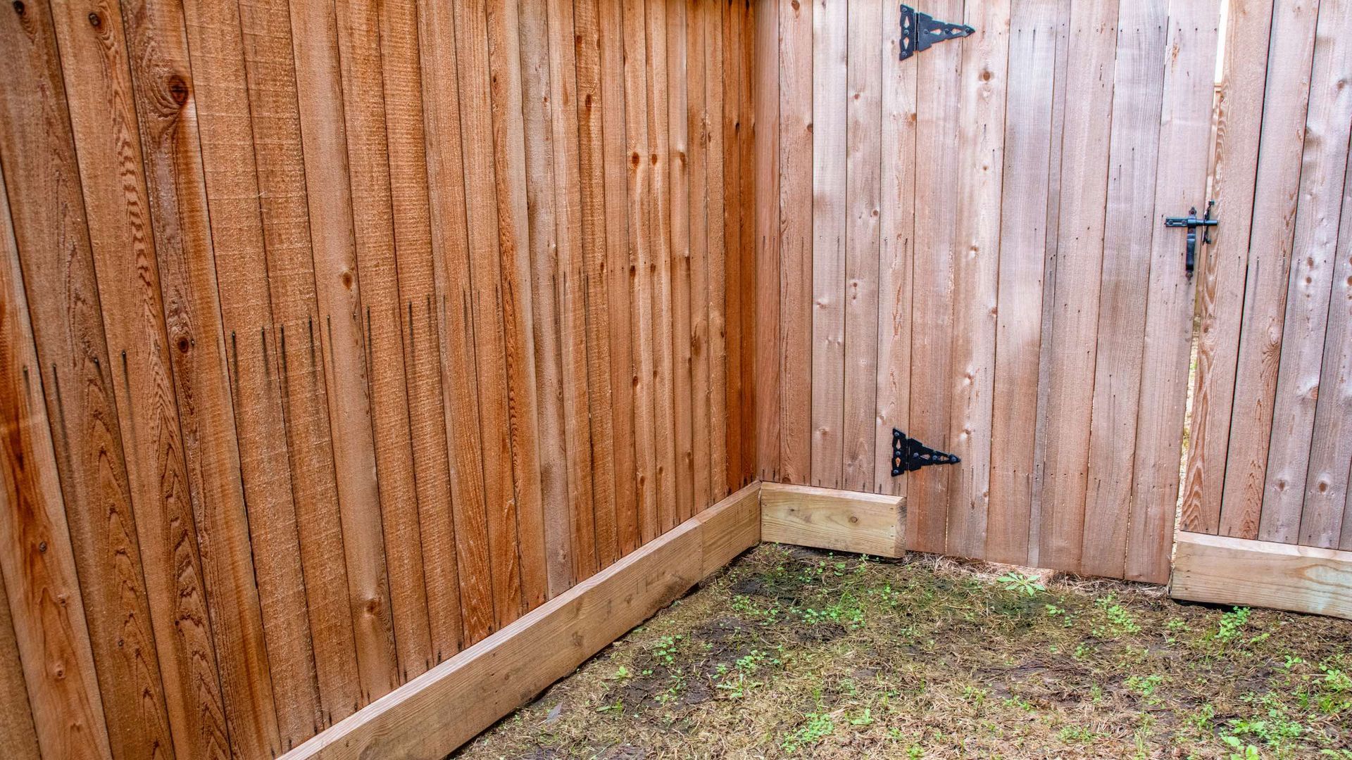 There is a wooden fence in the corner of the yard.