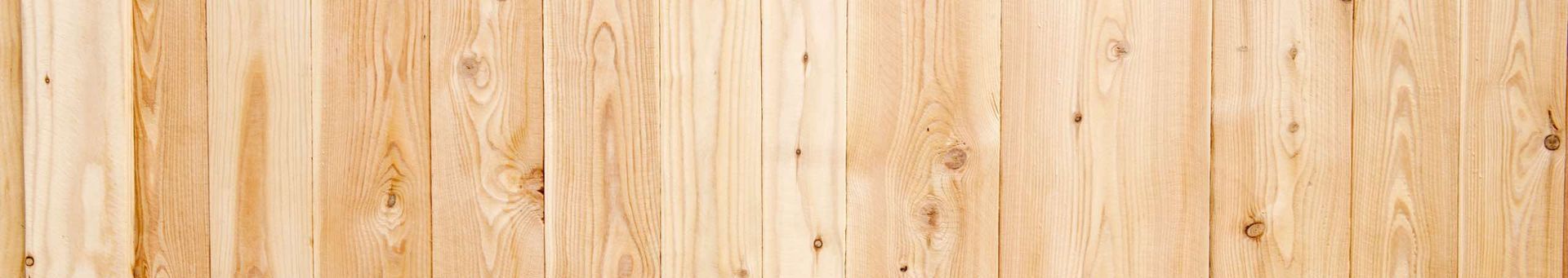 A close up of a wooden floor with a wooden fence in the background.