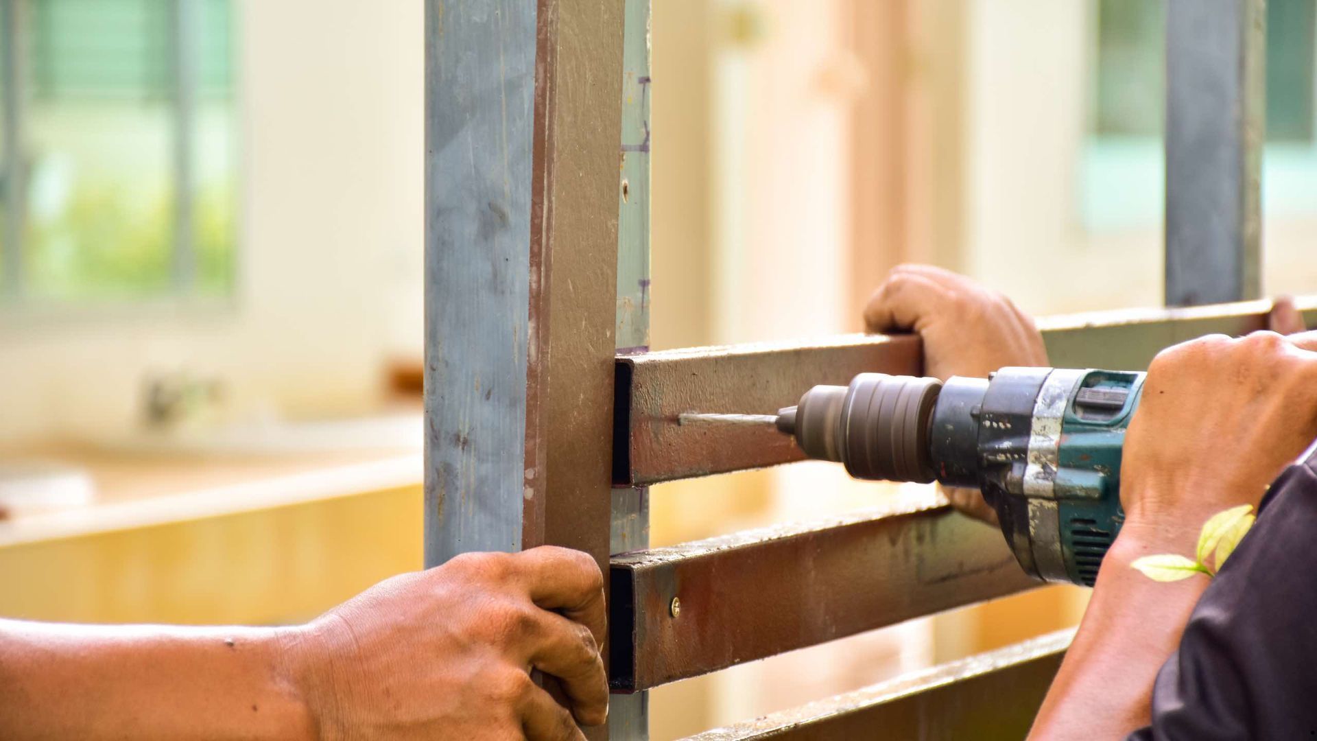 A man is using a drill to drill a hole in a piece of metal.