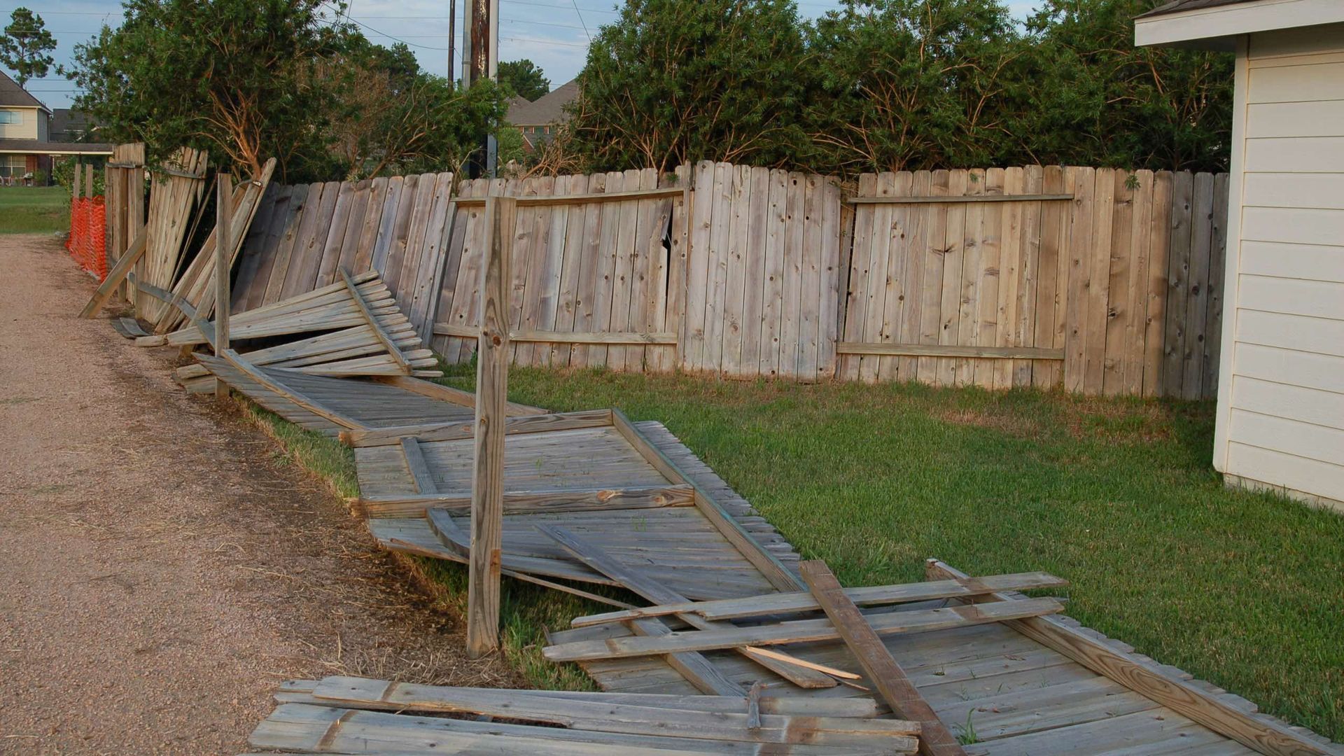 A wooden fence that has been damaged by a storm