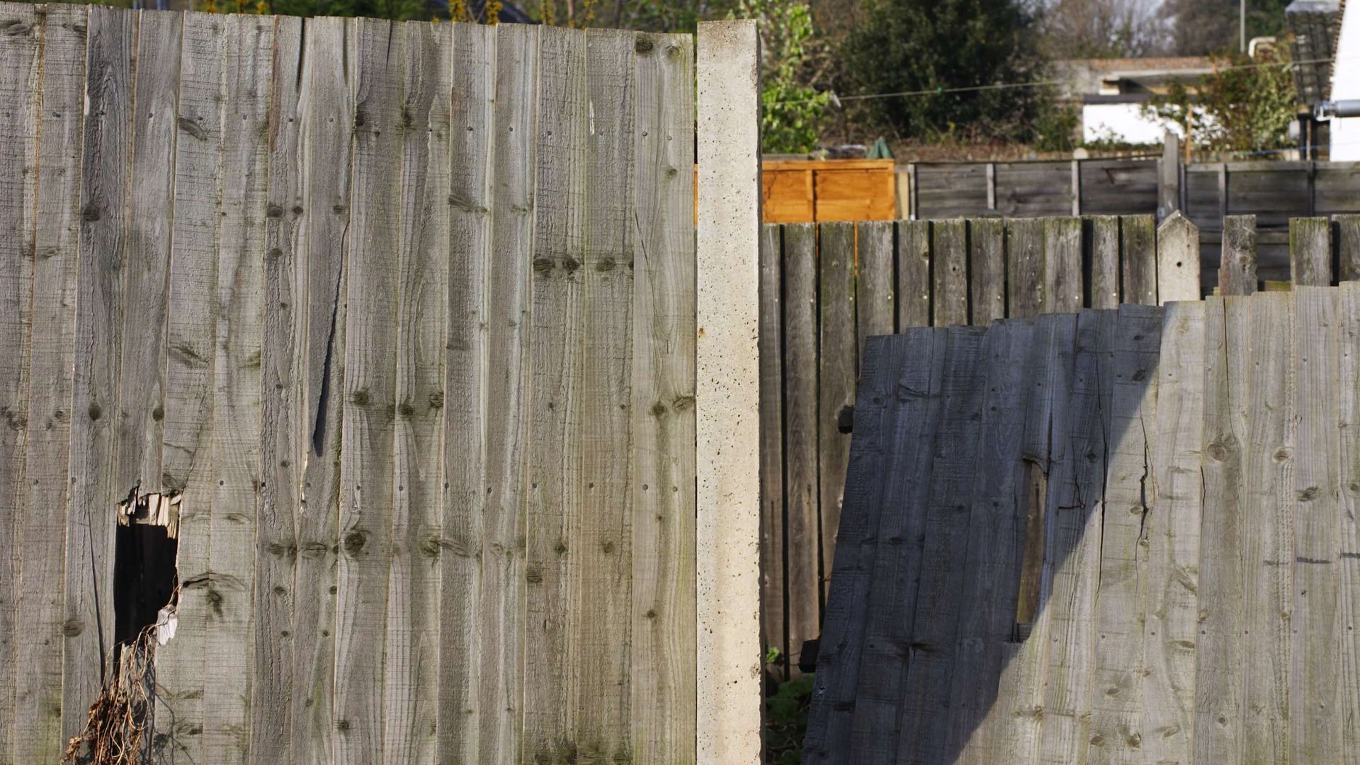 A wooden fence with a hole in it