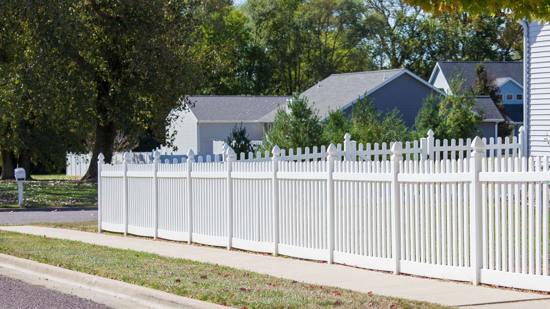 A white picket fence along a sidewalk in front of a house