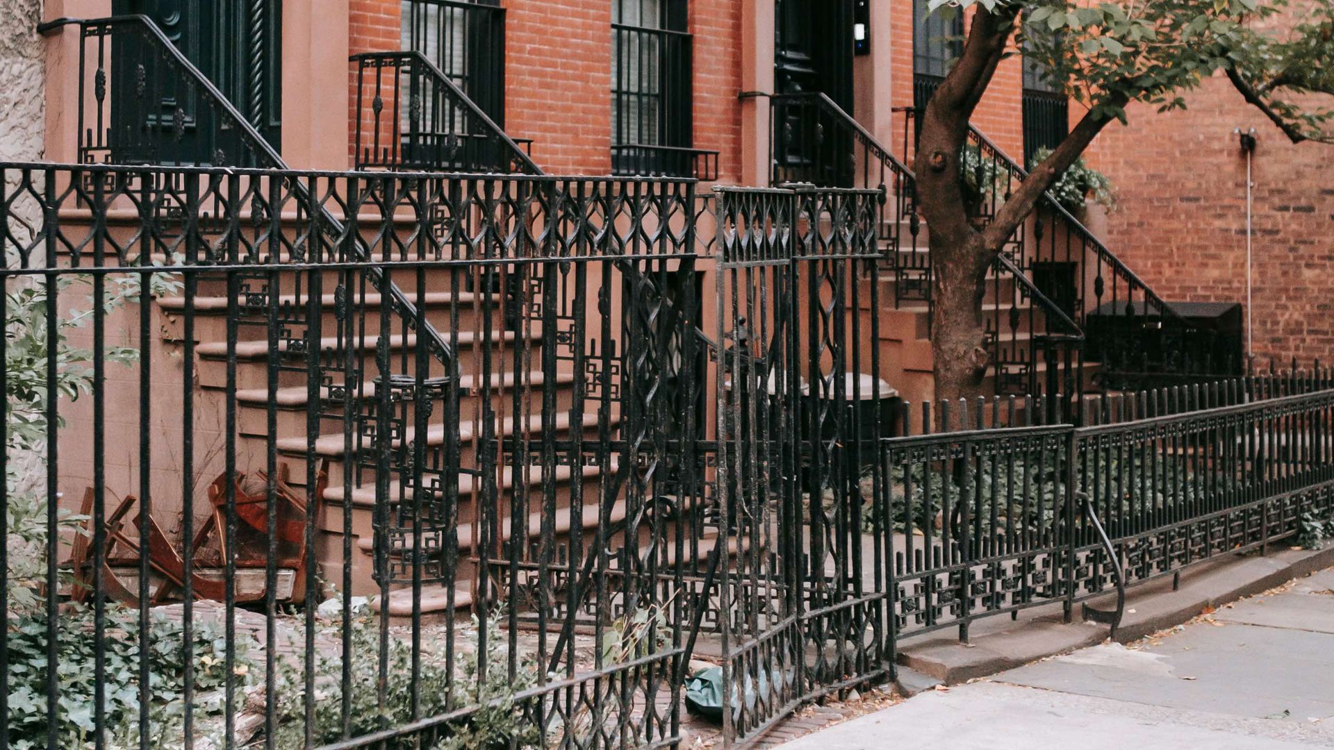 A black wrought iron fence surrounds a brick building with stairs.