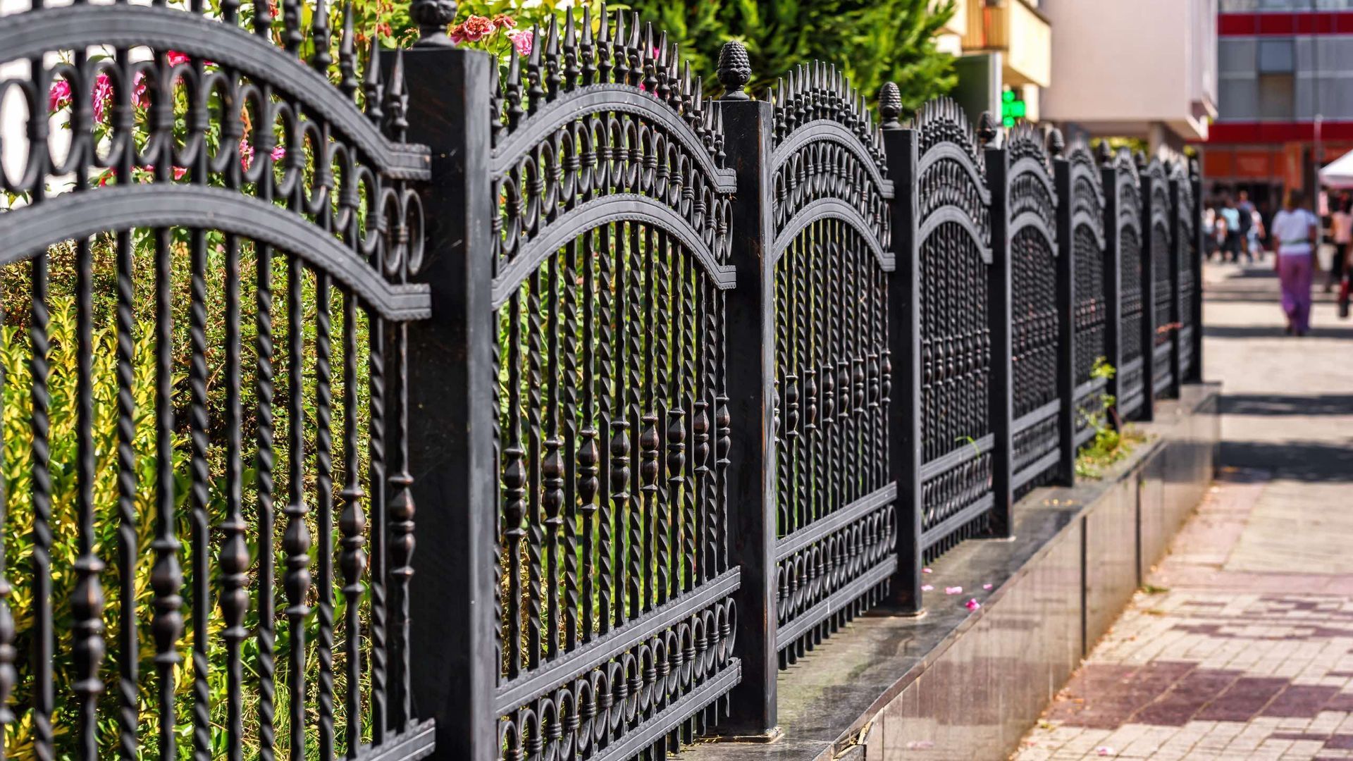 A row of wrought iron fences along a sidewalk.