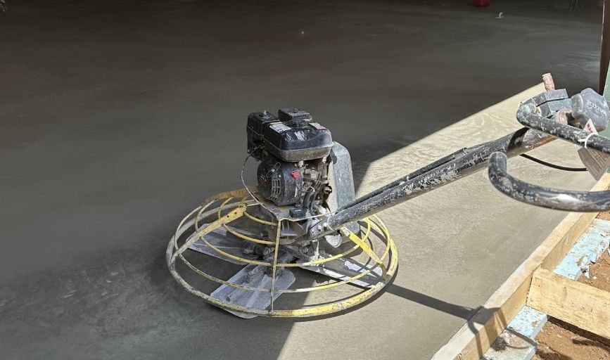 A person is using a trowel to finish a concrete floor.