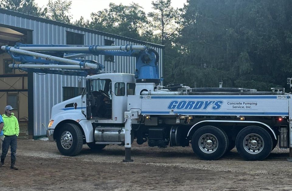 A cordy 's concrete pump truck is parked in front of a building.