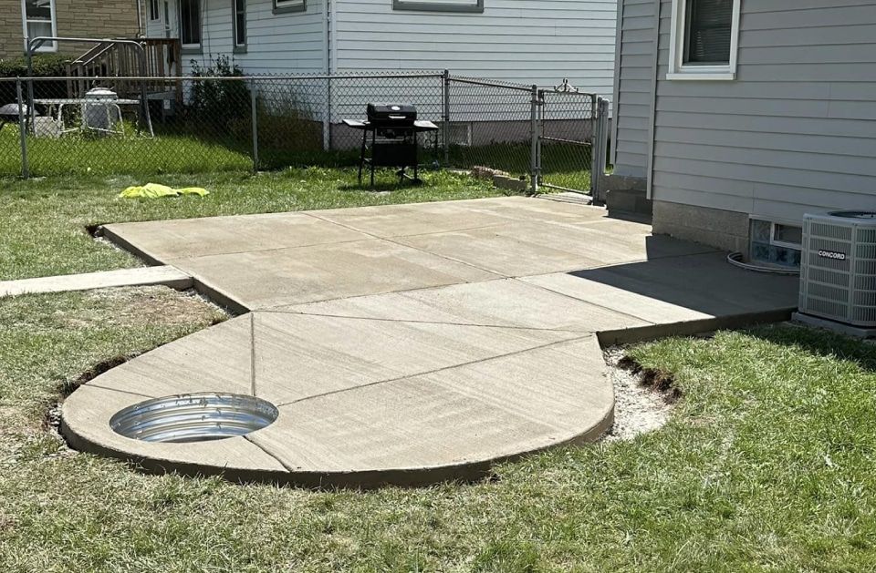 A concrete patio is being built in the backyard of a house