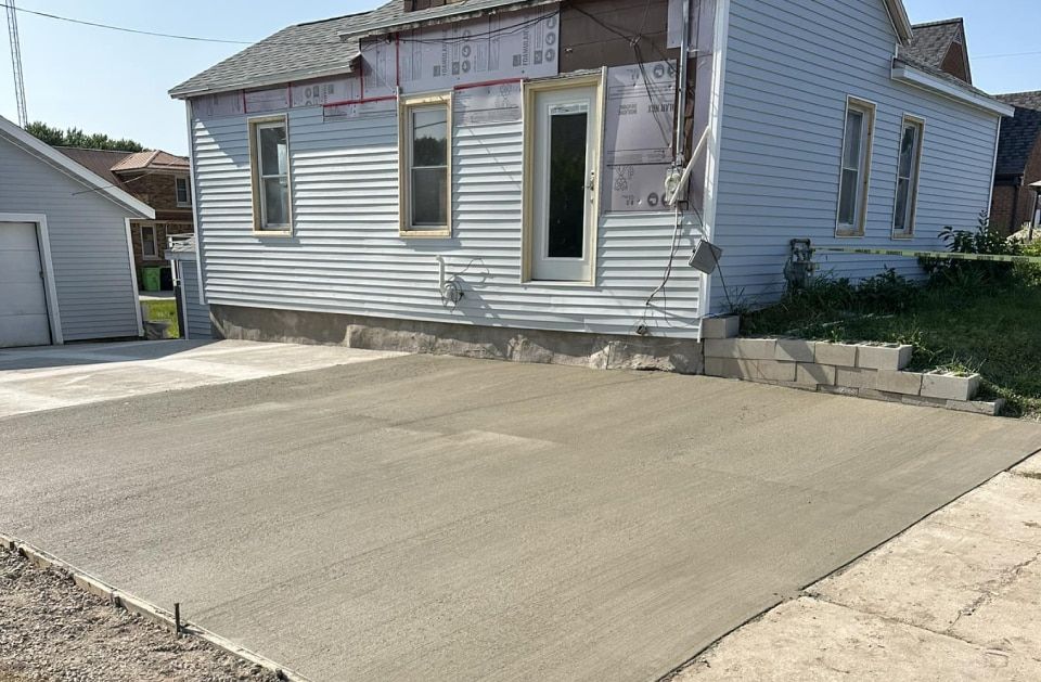 A white house with a concrete driveway in front of it.