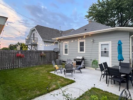 A house with a patio and a grill in the backyard.
