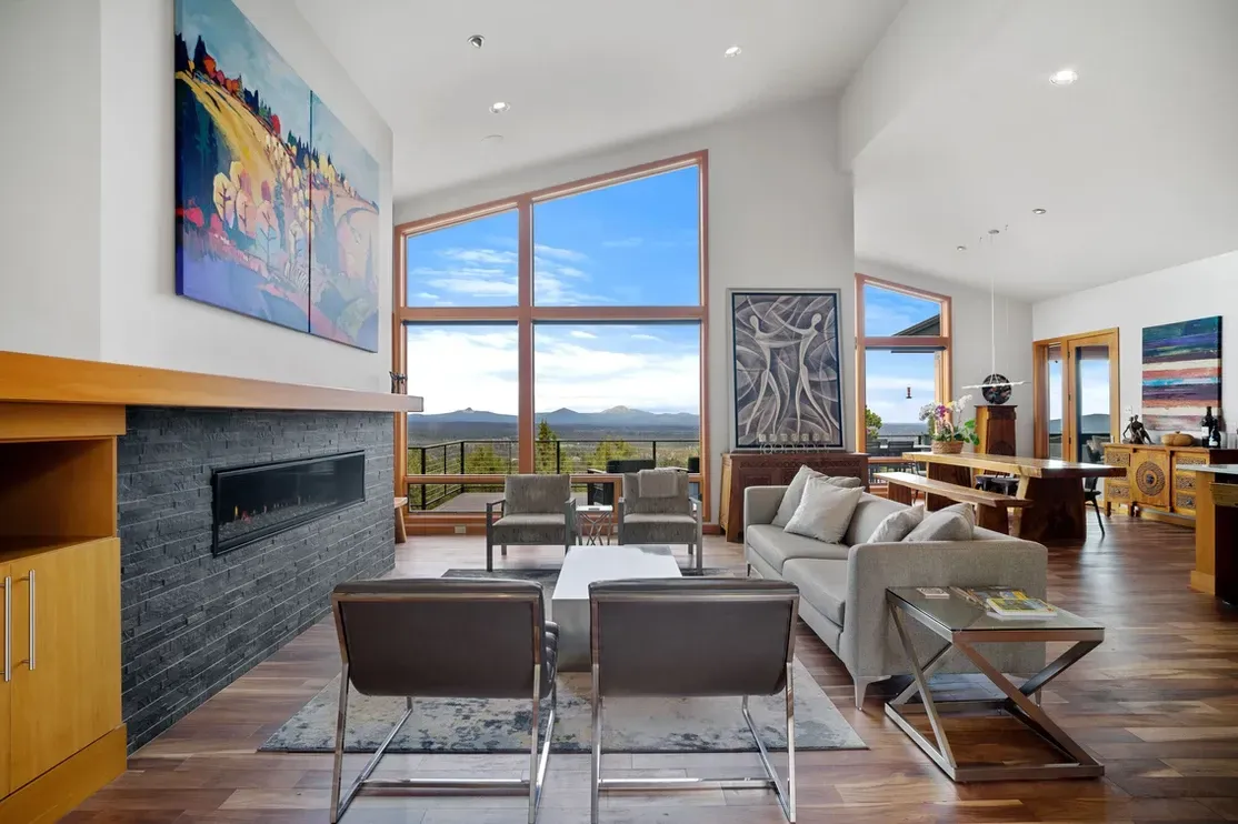 Living room with wide wood mantel, fireplace, and large windows with view