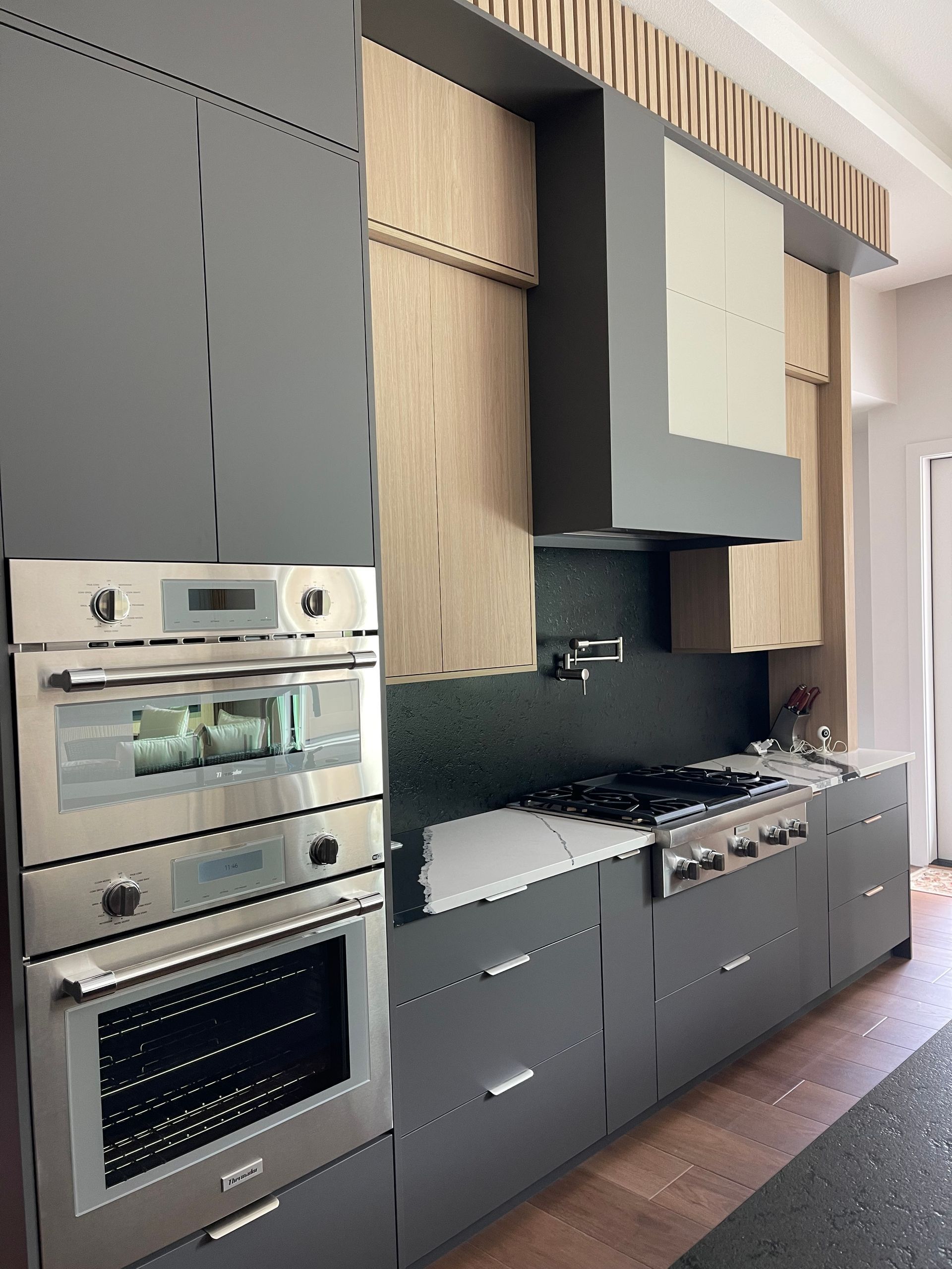 Gray and wood-toned modern kitchen with stainless steel appliances.