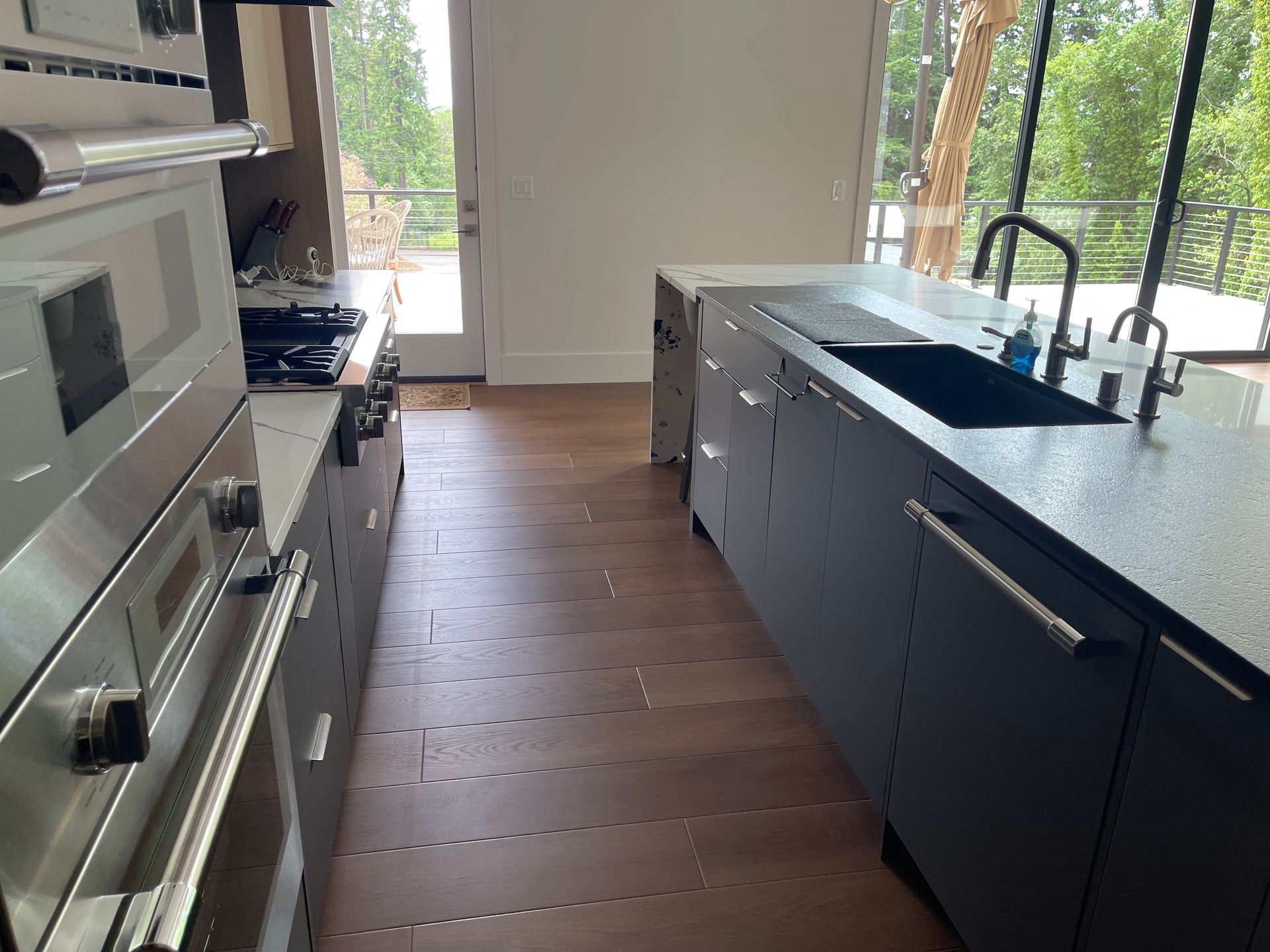 Modern kitchen with gray cabinets, stainless steel appliances, and a large island with a sink.