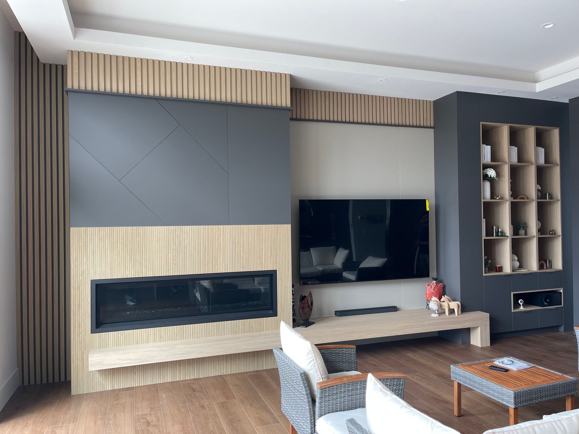 Living room with wood paneling, fireplace, TV, and shelving unit.