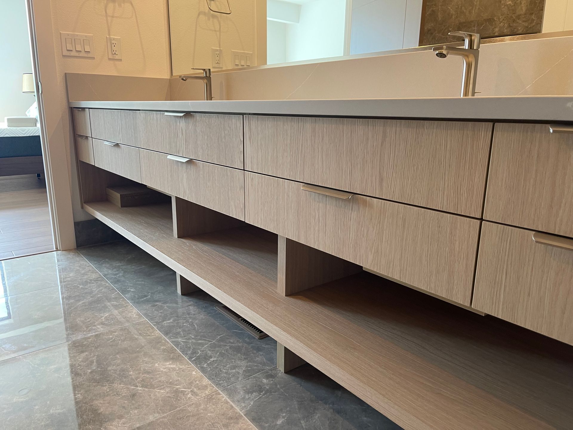 Light wood vanity with open shelving in a modern bathroom.