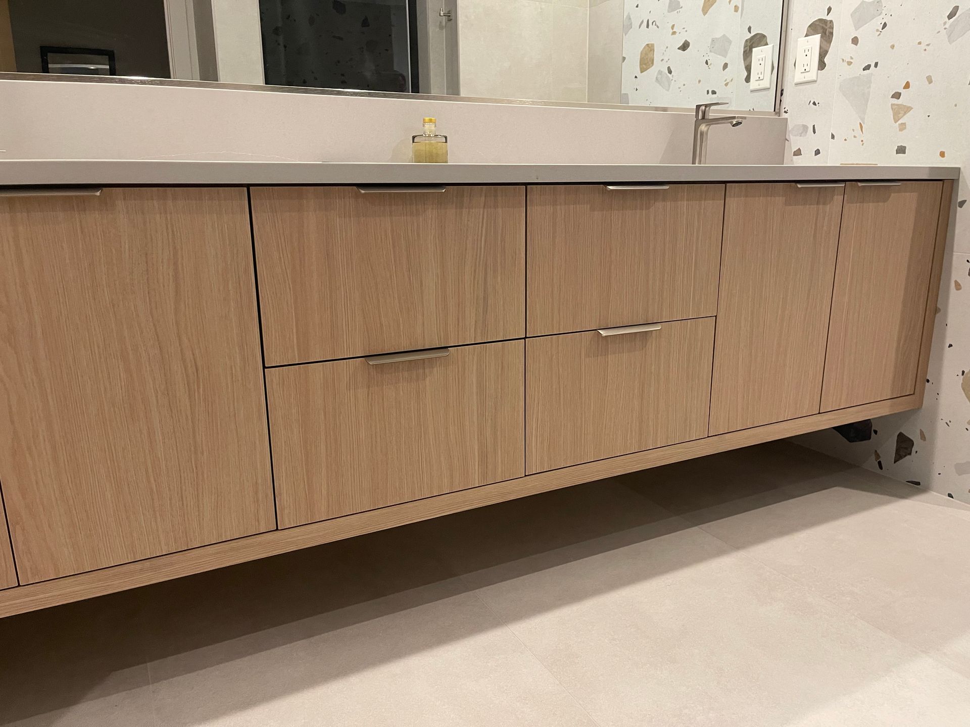 Wooden bathroom vanity with light-colored countertop, drawers, and silver handles.