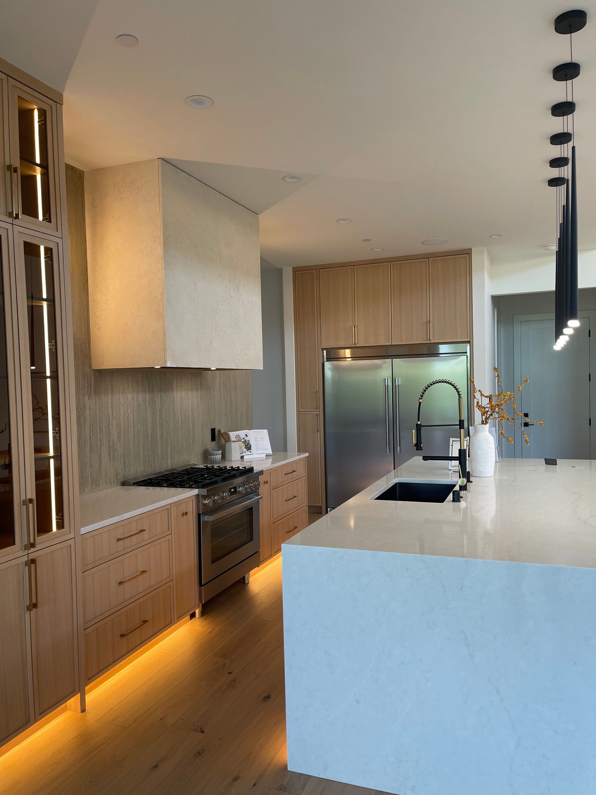 Modern kitchen with wood cabinets, white island, stainless steel appliances, and pendant lights