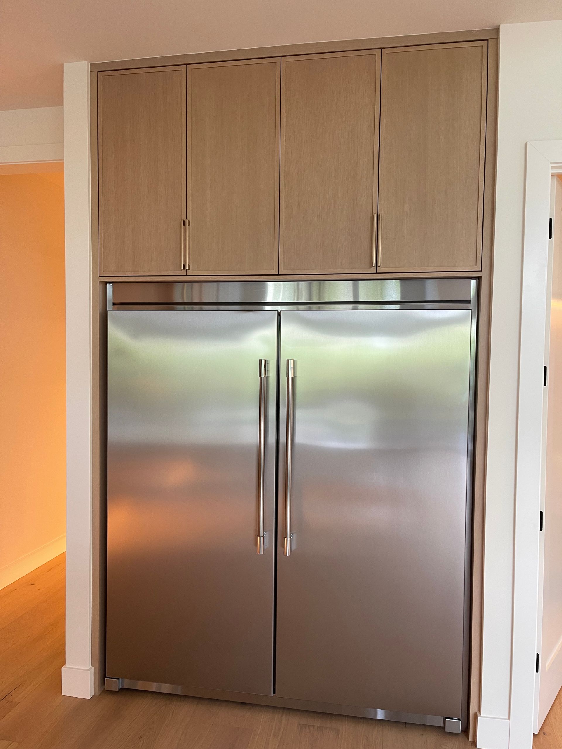 Built-in stainless steel double-door refrigerator with wood cabinet surround in a kitchen alcove in Portland, Oregon, WA