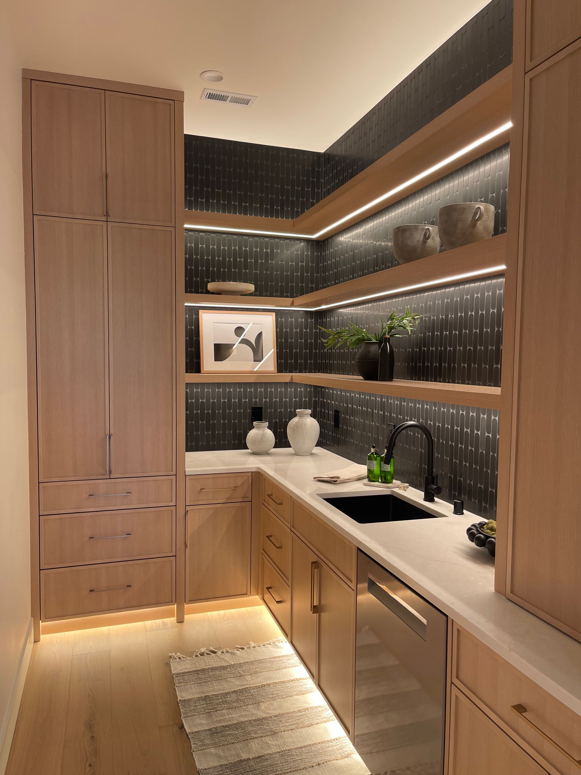 Modern kitchen with wood cabinets, black tile backsplash, under-cabinet lighting, and a white countertop in Portland, Oregon
