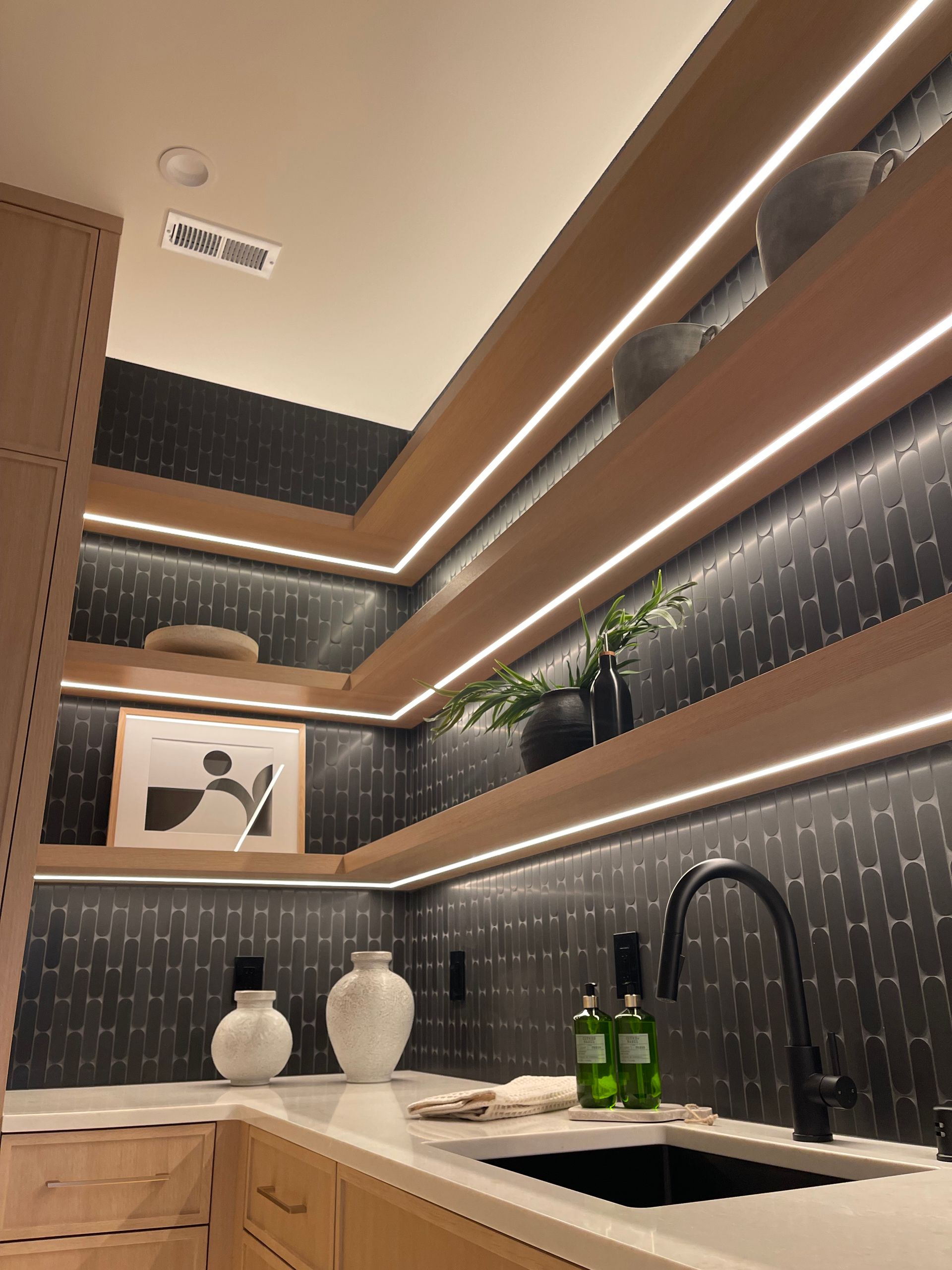 Modern kitchen corner with wood shelves, black tile backsplash, sink, plants, and framed art. in Portland, Oregon, WA