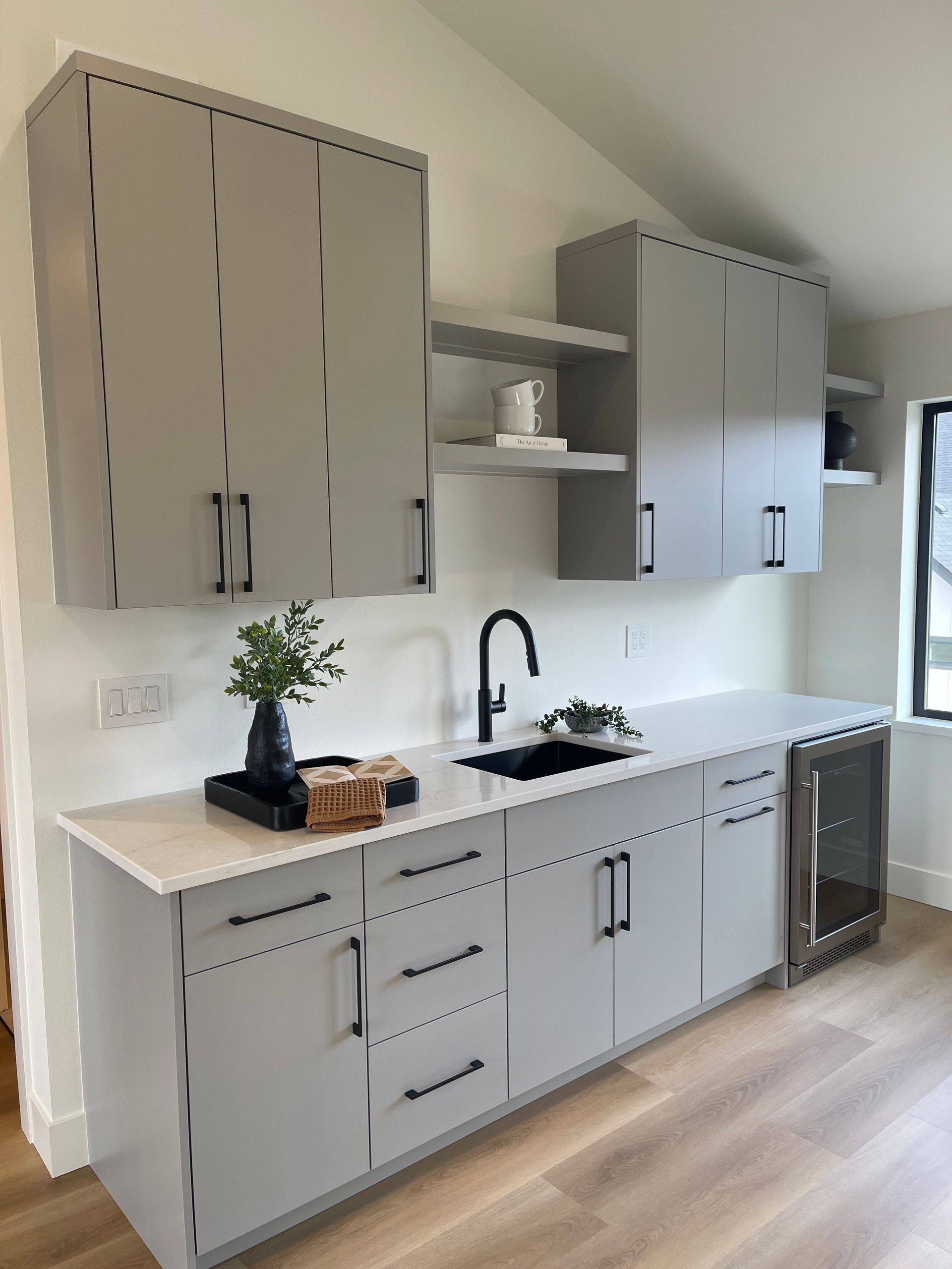 Modern kitchen with gray cabinets, white countertop, black faucet, and light wood flooring in Portland, Oregon, WA