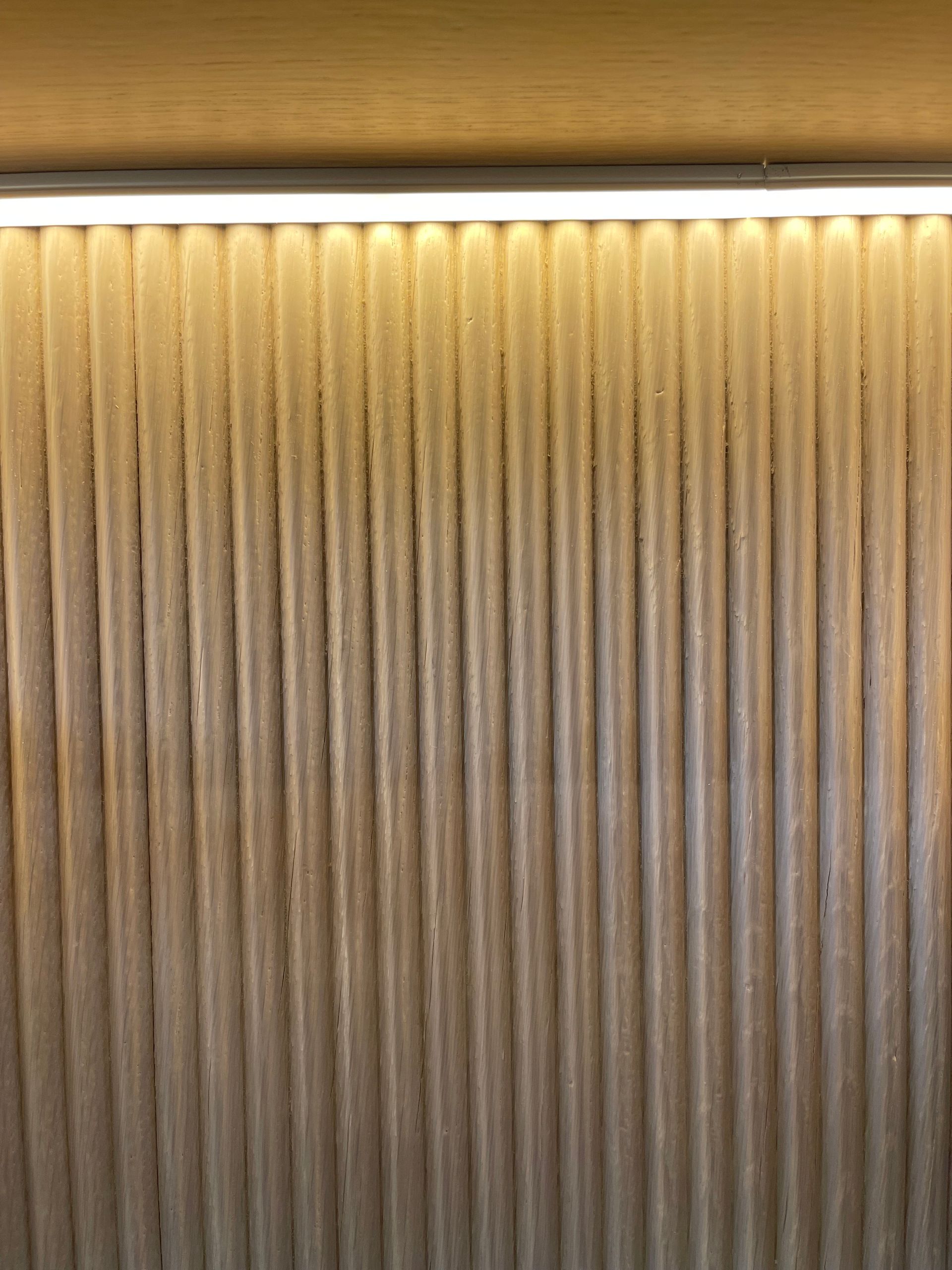 Warm-lit textured wall with vertical ridges beneath a row of ceiling spotlights