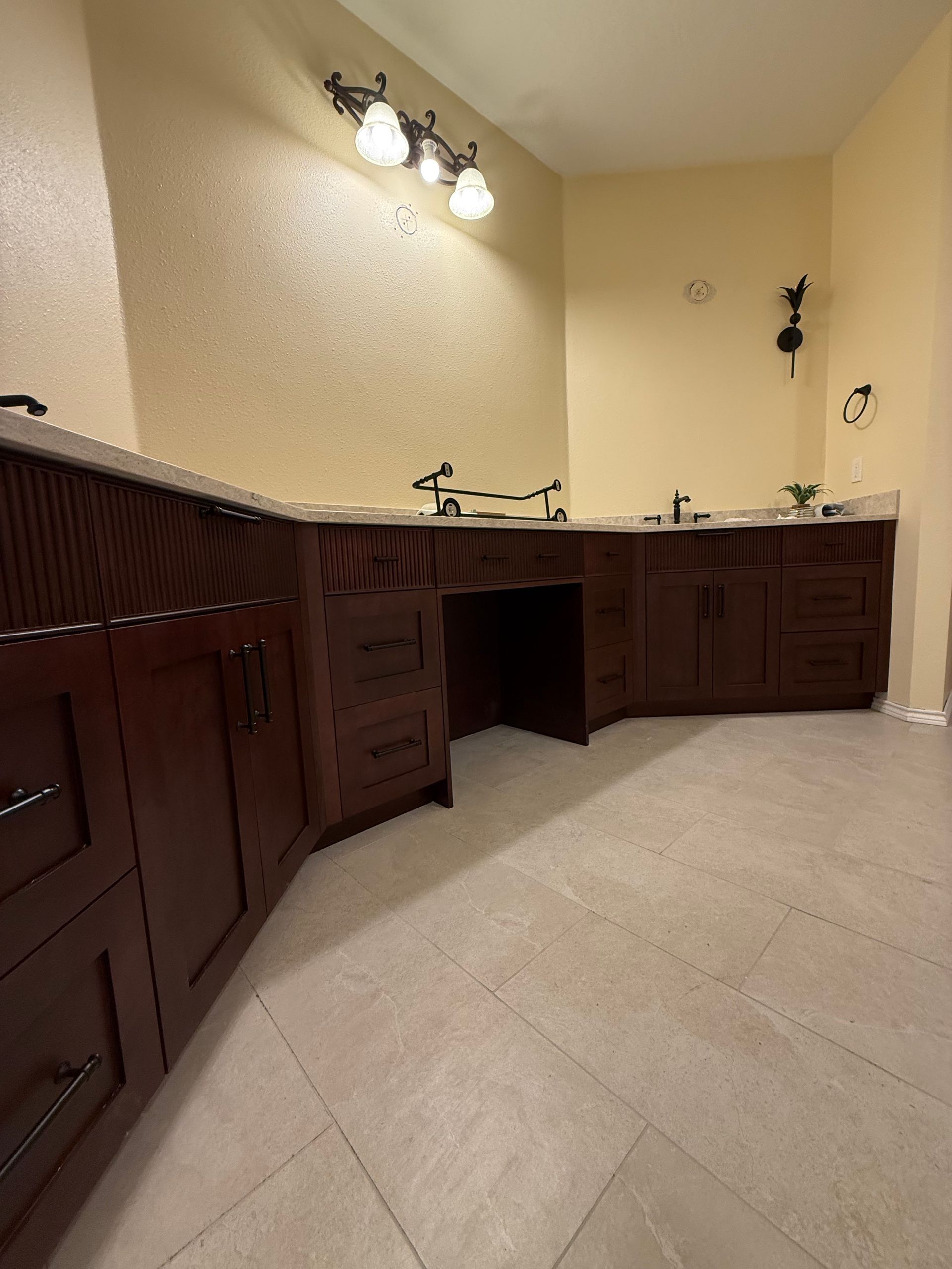 Dark wood bathroom cabinets with a light countertop and beige walls.
