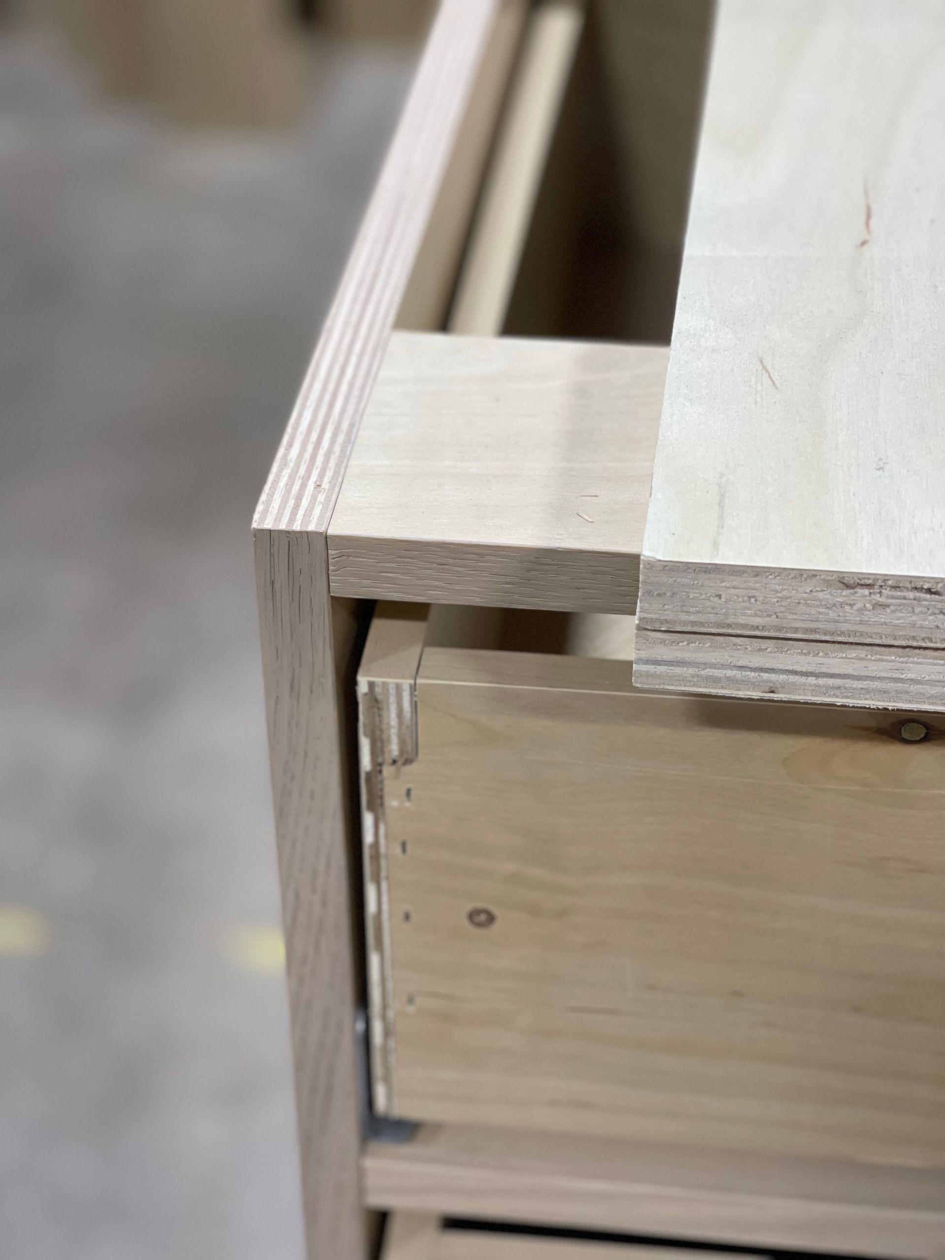 Cabinet frame corner with a drawer partially open, showing construction details.