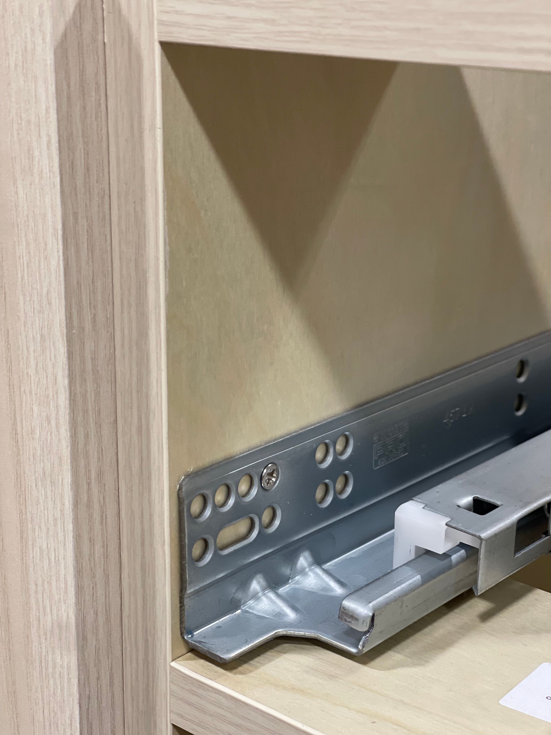 Drawer slide hardware attached to the inside of a cabinet.