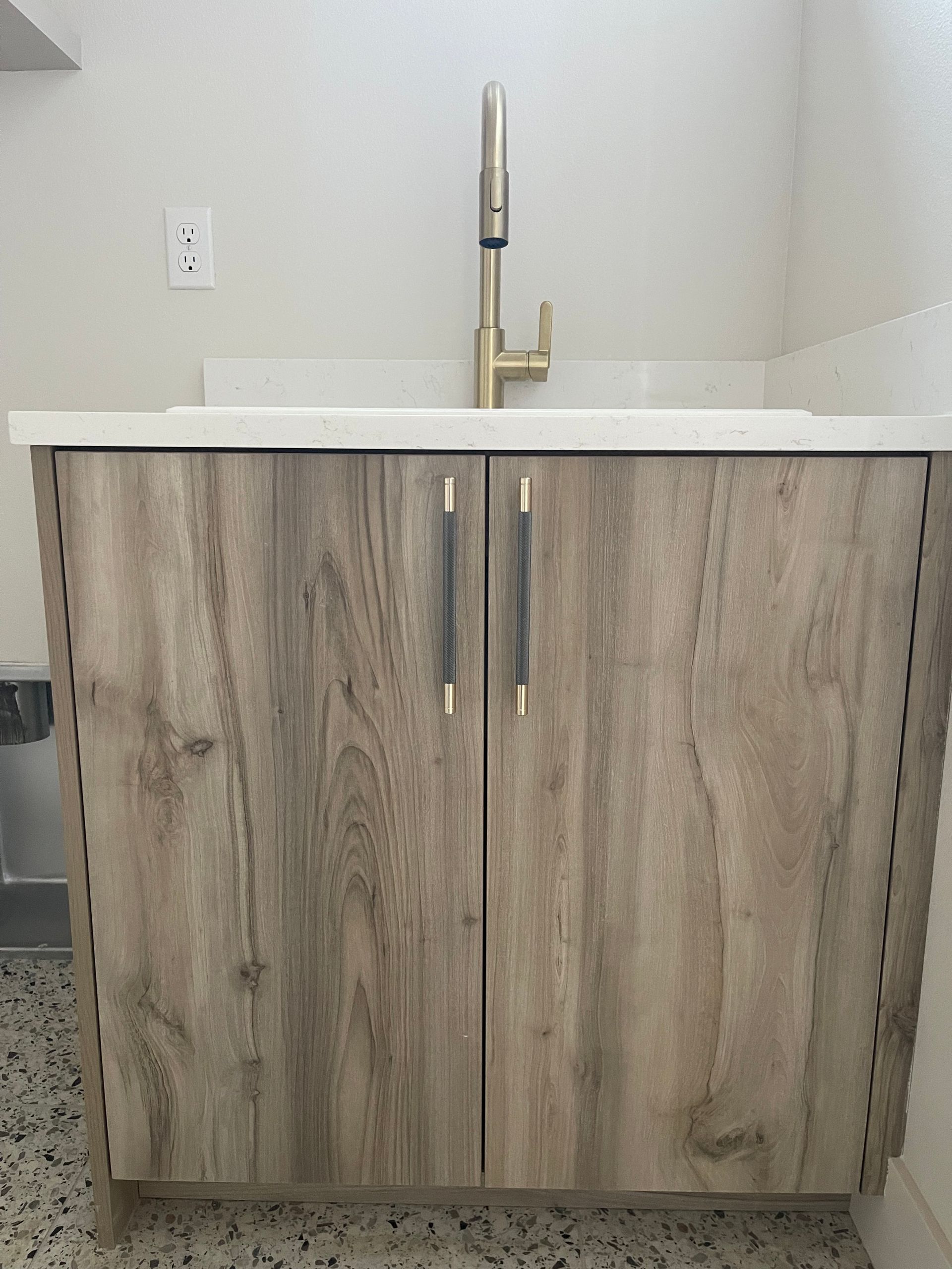 Wooden bathroom cabinet with gold faucet and white countertop in room. custom bathroom vanities manufacturing in Portland