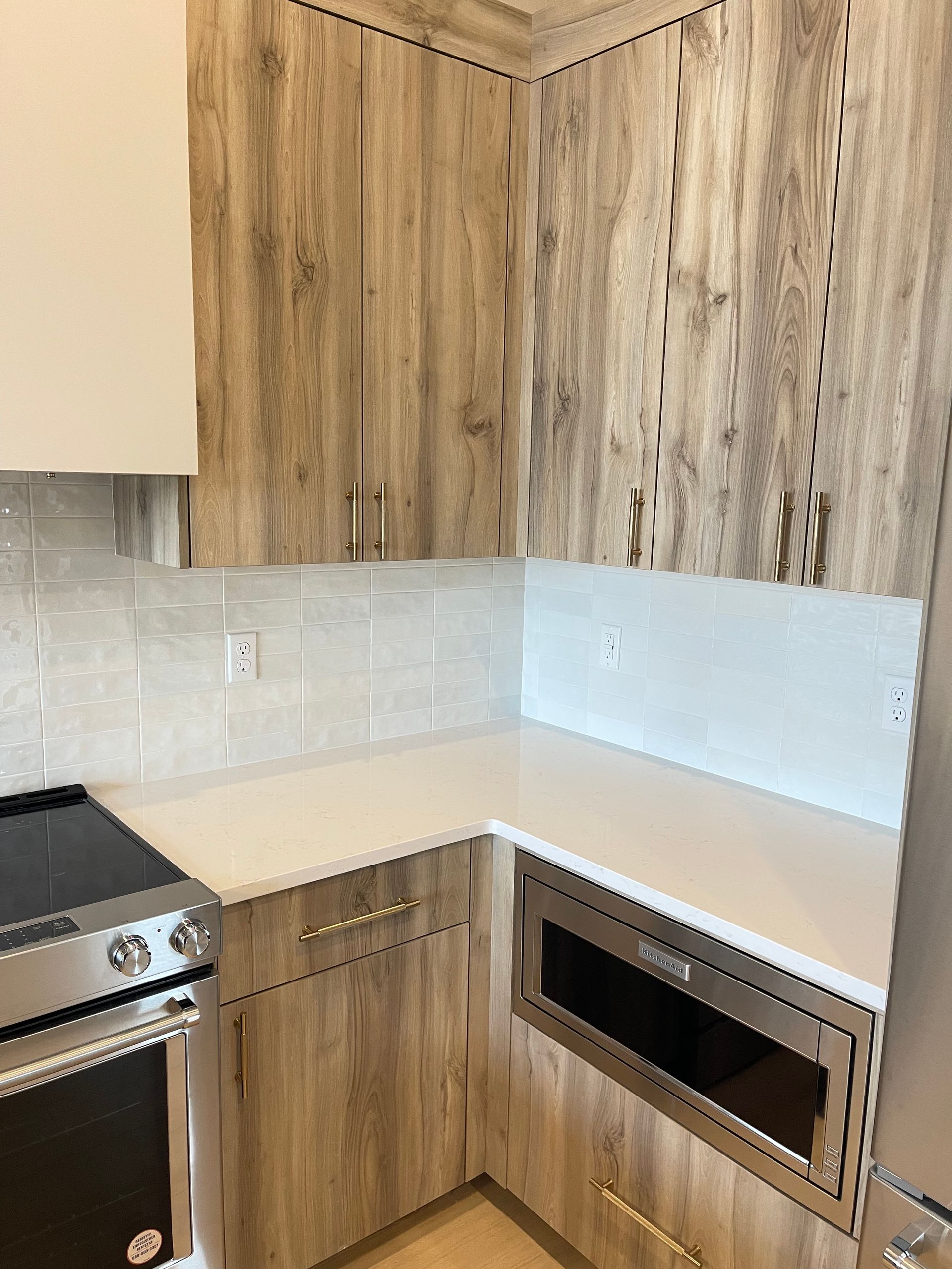 Kitchen with light wood grain cabinets, white countertops, and a stainless steel oven.
