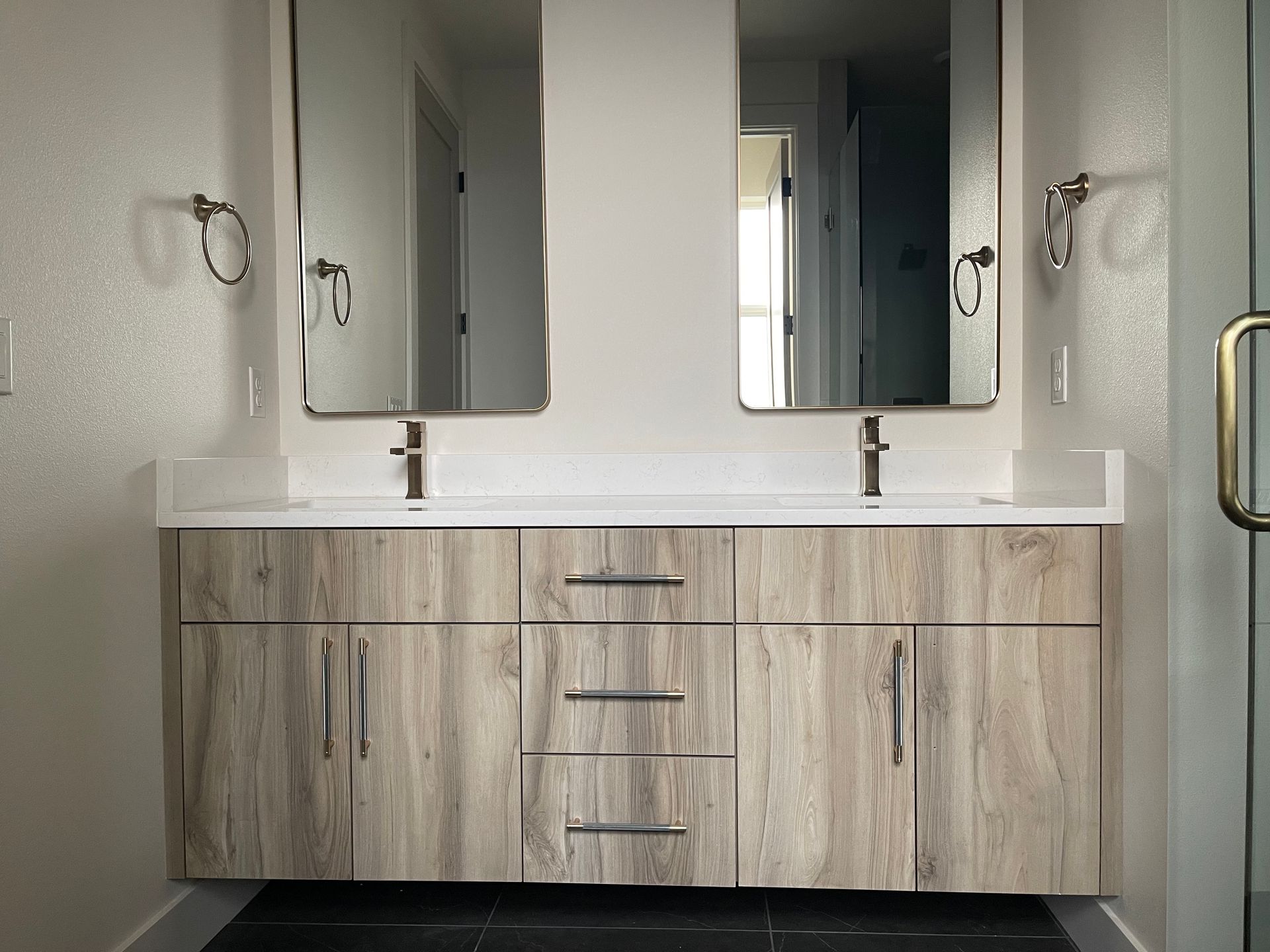 Bathroom vanity with two mirrors, silver fixtures, and wood-grain cabinet doors. White countertop. pro-techwoodworking