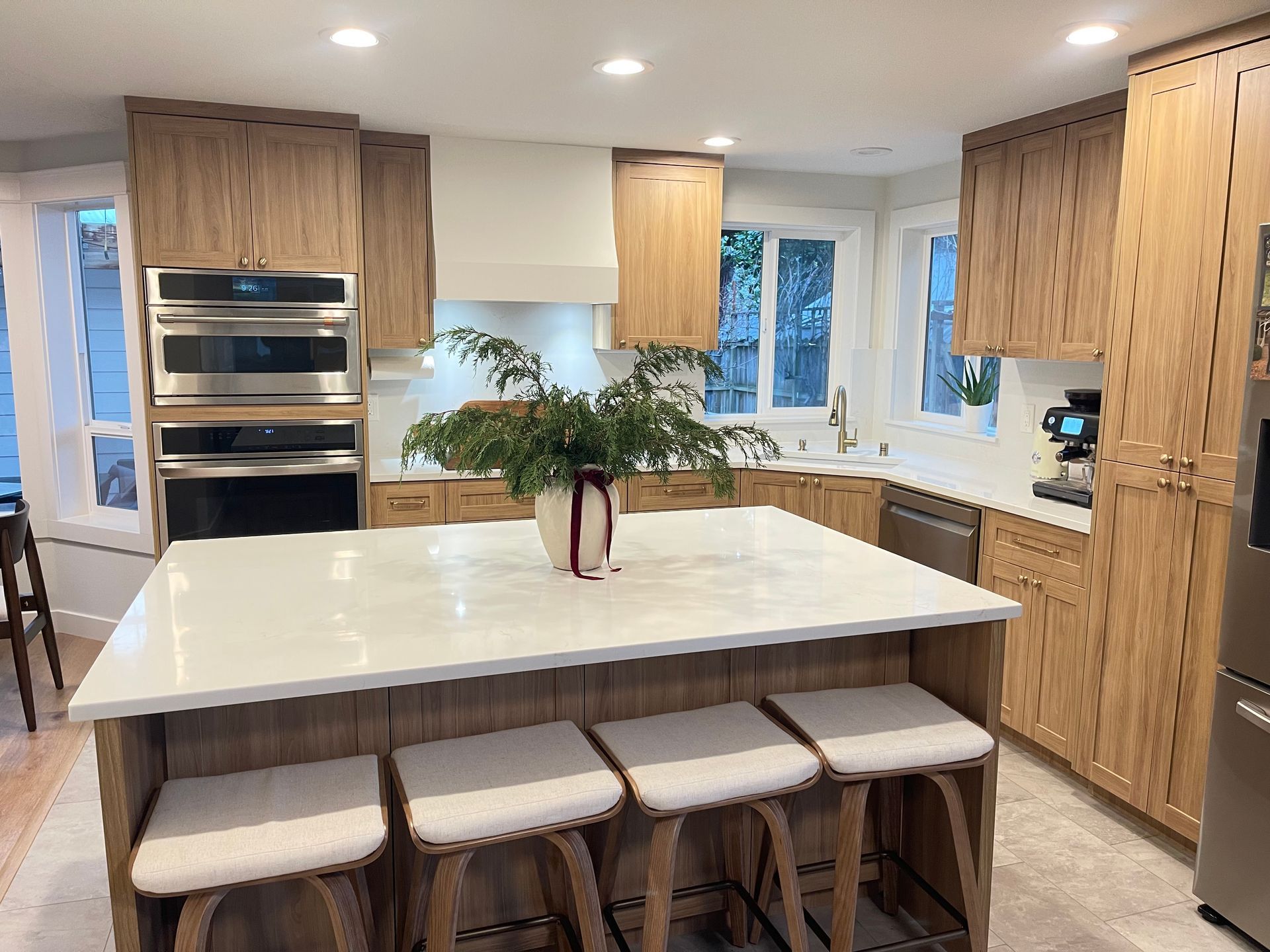 Kitchen with light wood cabinets, white countertops, island with seating, and stainless steel appliances. Custom kitchen in Portland. 