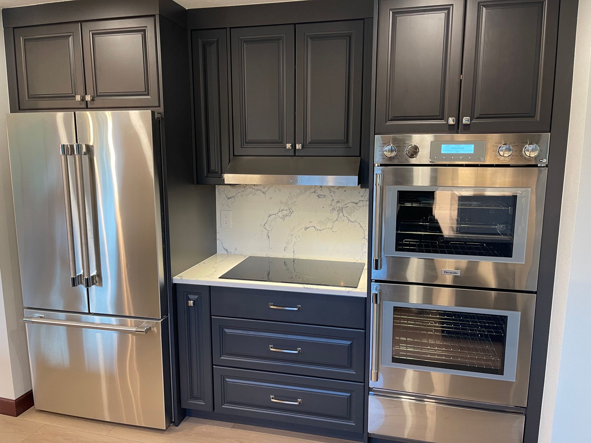 Custom kitchen in Portland with stainless steel appliances, dark gray cabinets, and a cooktop.