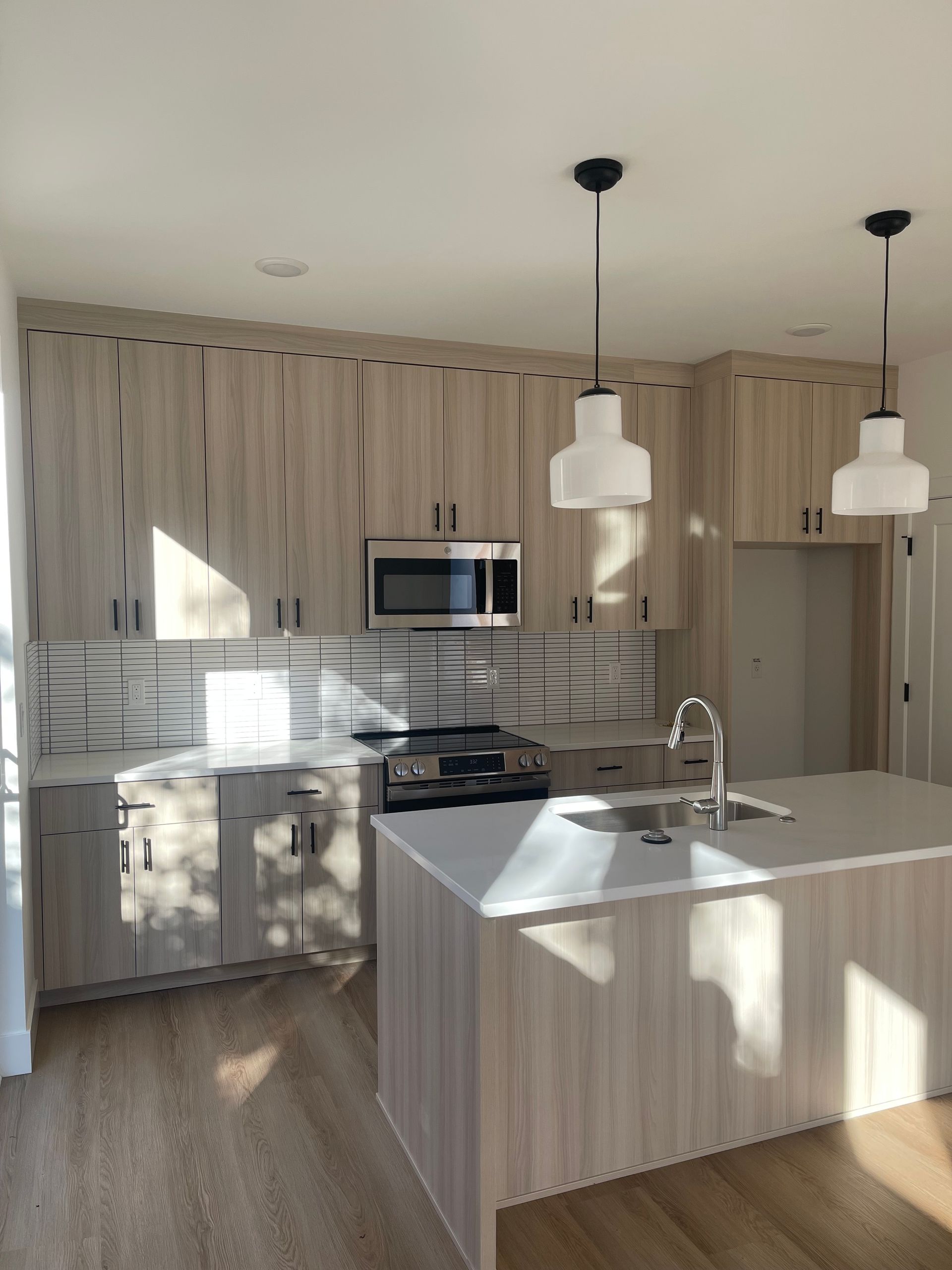 Modern kitchen with light wood cabinets, stainless steel appliances, and island pro-techwoodwoorking.