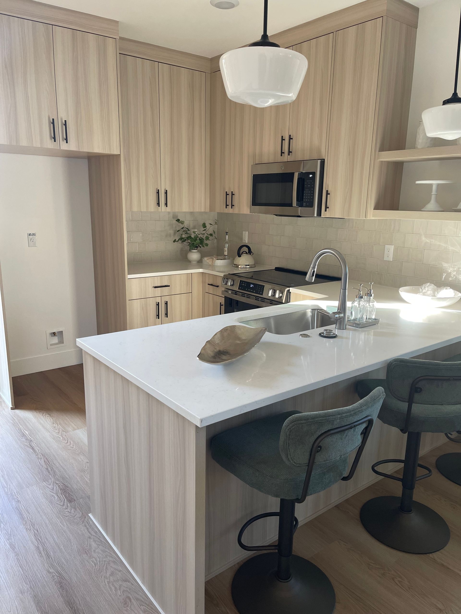 Modern kitchen with light wood cabinets, white countertops, and teal bar stools pro-techwoodwoorking.